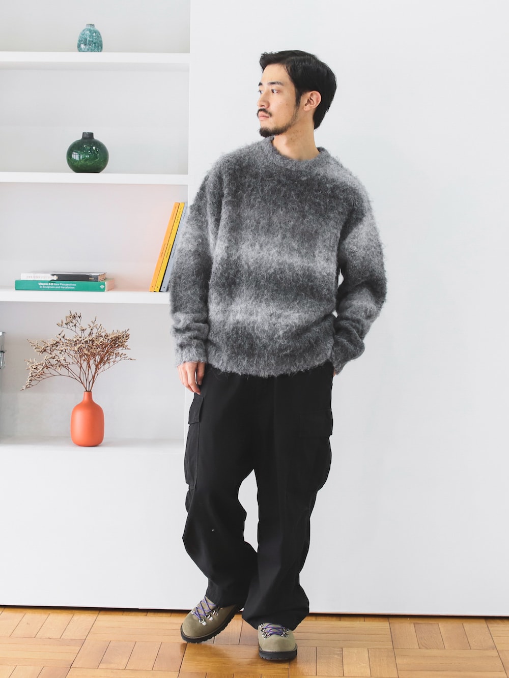 グレー系のニット/セーター、ブラック系のカーゴパンツ、ベージュ系のブーツを着用したメンズの秋コーディネートの2枚目の写真