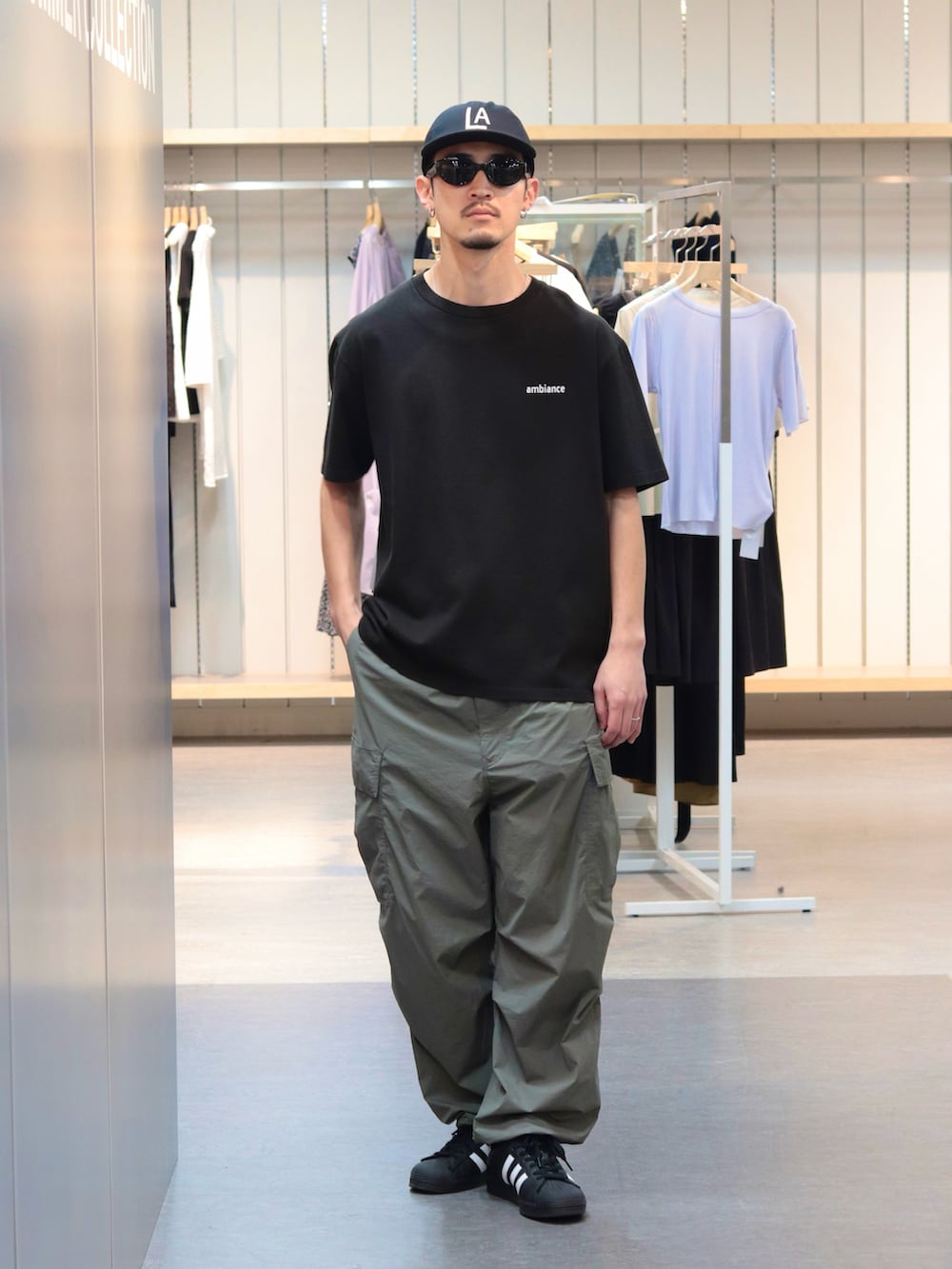 ブラック系のTシャツ/カットソー、グリーン系のカーゴパンツ、ブラック系のキャップを着用したメンズの春コーディネートの2枚目の写真