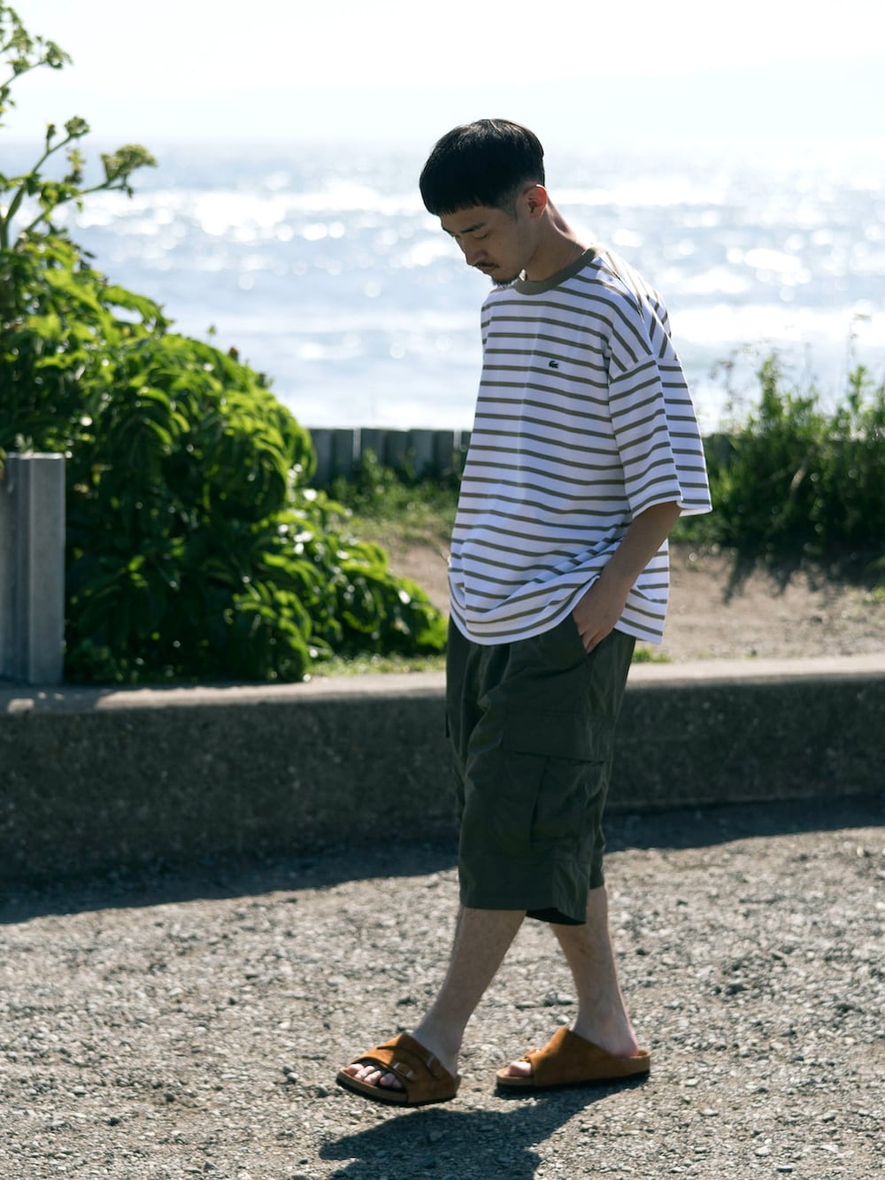 グリーン系のカーゴパンツ、ベージュ系のTシャツ/カットソーを着用したメンズの夏コーディネートの2枚目の写真