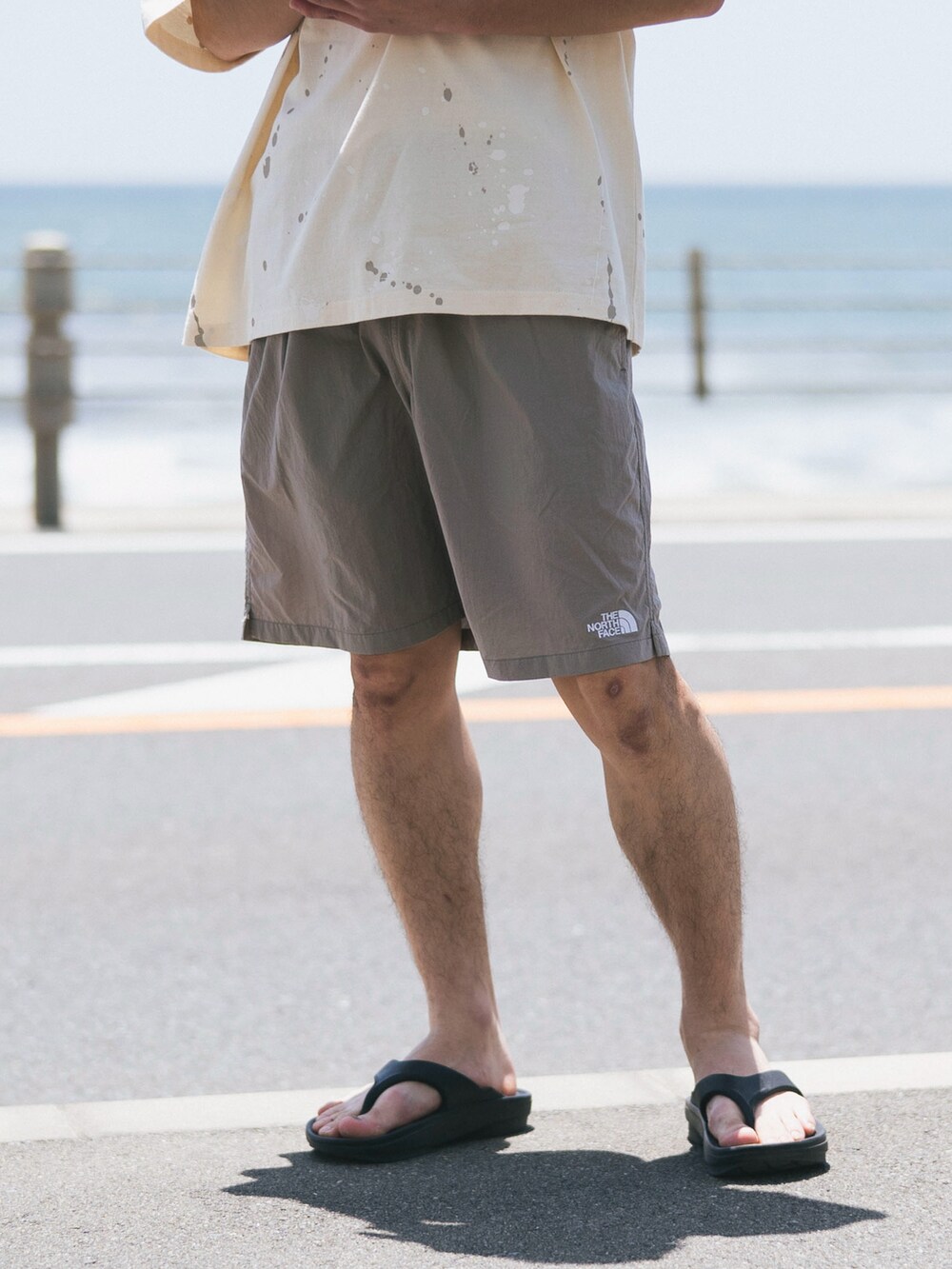 ホワイト系のTシャツ/カットソー、グレー系のその他パンツ、ブラック系のサンダルを着用したメンズの夏コーディネートの2枚目の写真