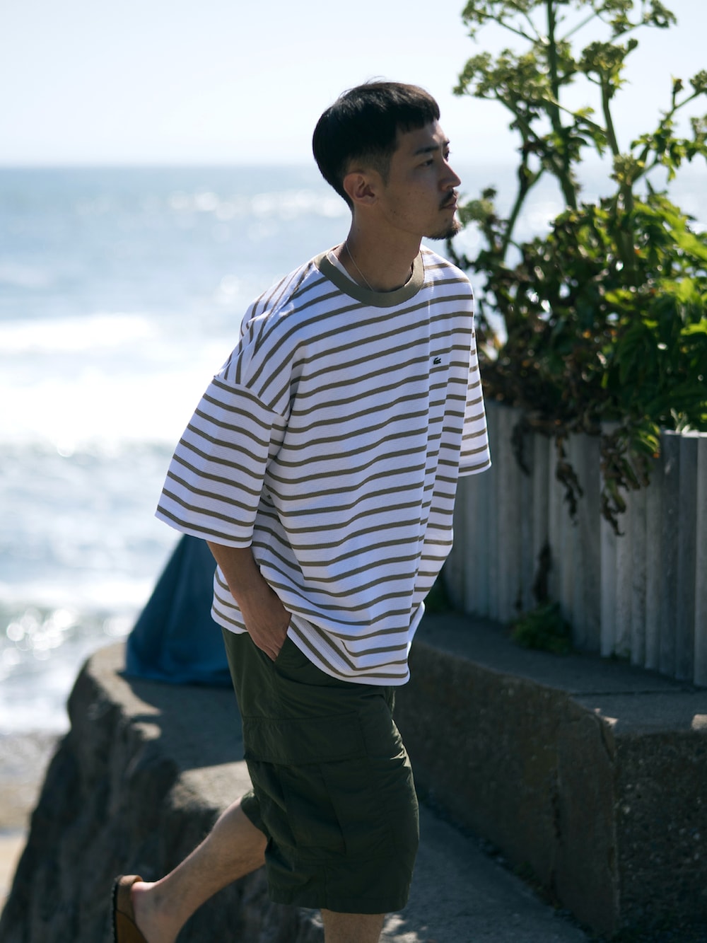 グリーン系のカーゴパンツ、ベージュ系のTシャツ/カットソーを着用したメンズの夏コーディネートの3枚目の写真