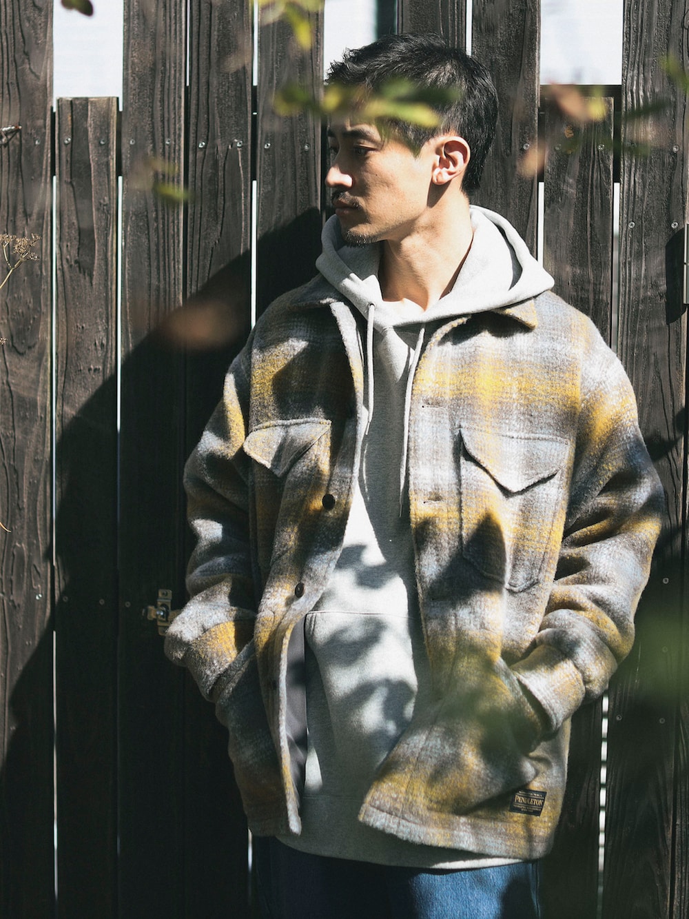 イエロー系のブルゾン、ブルー系のデニムパンツ、グレー系のパーカーを着用したメンズの秋コーディネートの4枚目の写真