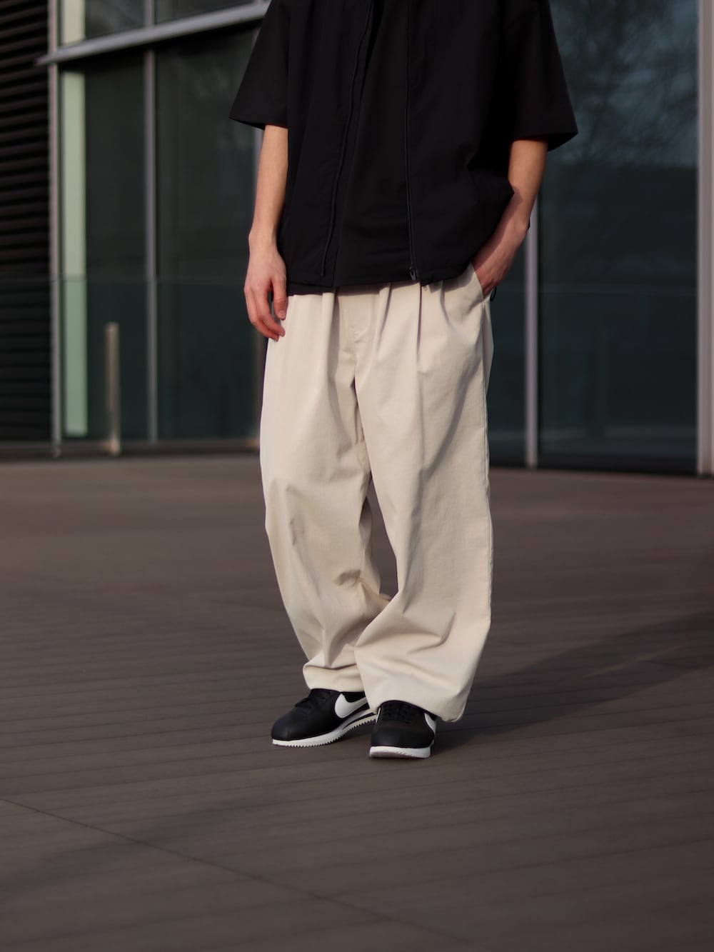 ブラック系のTシャツ/カットソー、ホワイト系のチノパンツ、ブラック系のスニーカーを着用したメンズの春コーディネートの5枚目の写真