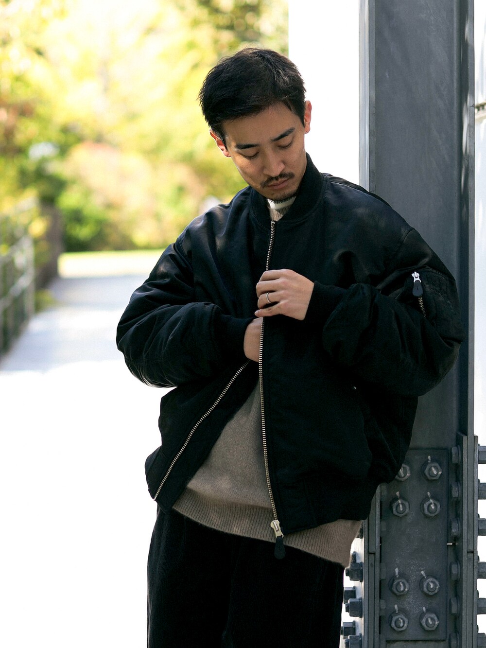 ブラック系のMA-1、ブラック系のスニーカー、ベージュ系のニット/セーターを着用したメンズの春コーディネートの3枚目の写真