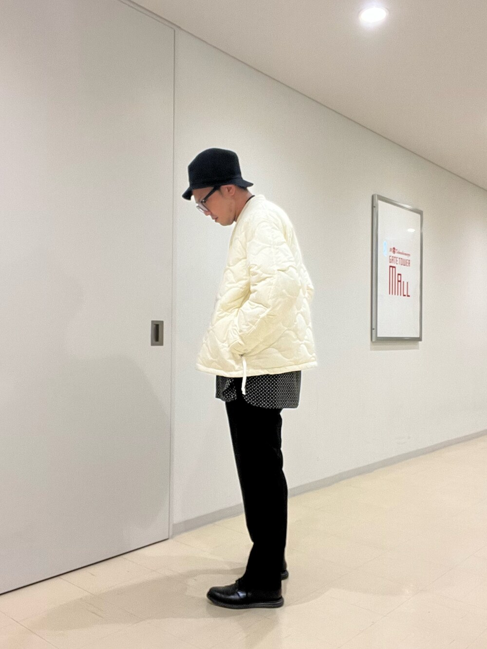 ブラック系のニット/セーター、ベージュ系のシャツ/ブラウス、ベージュ系のダウンジャケット/コートを着用したメンズの秋コーディネートの2枚目の写真