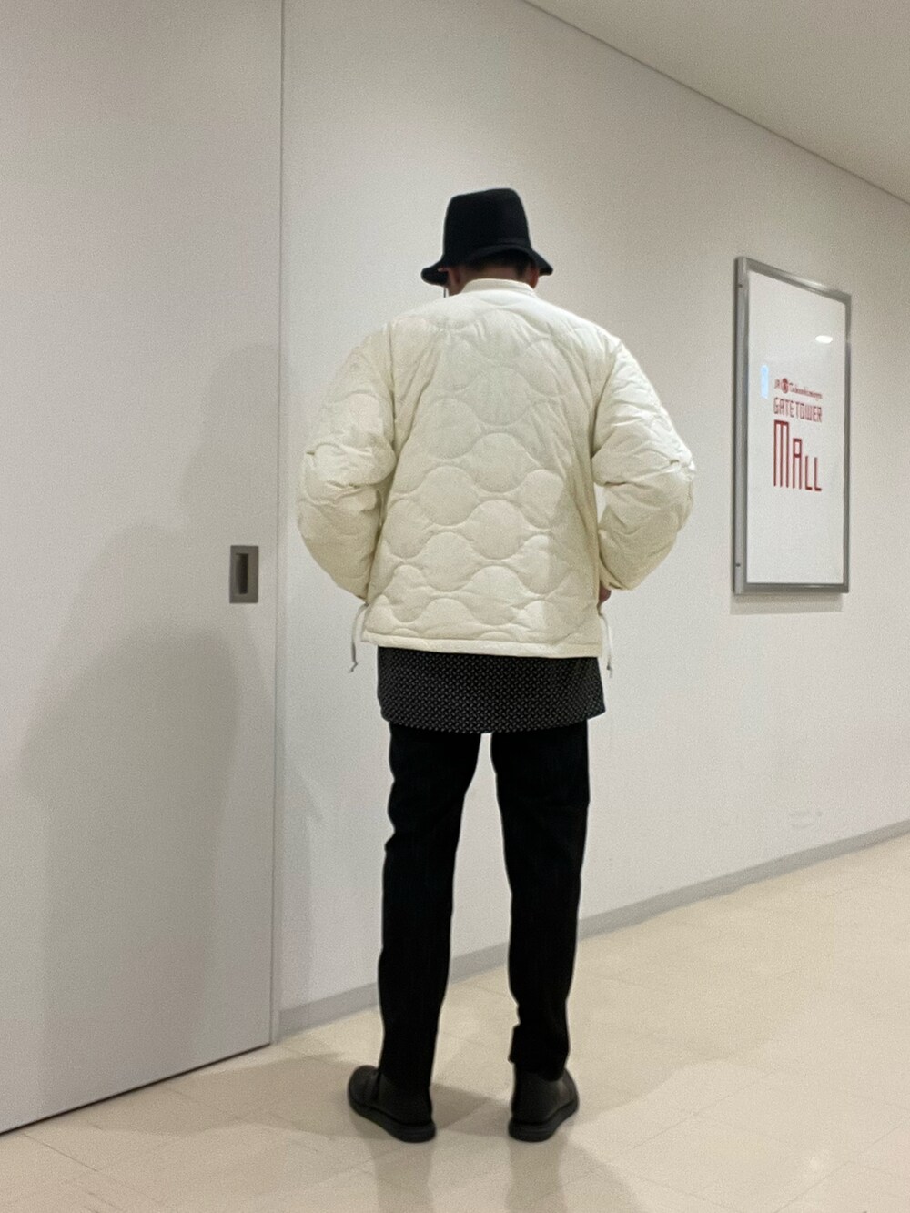 ブラック系のニット/セーター、ベージュ系のシャツ/ブラウス、ベージュ系のダウンジャケット/コートを着用したメンズの秋コーディネートの3枚目の写真