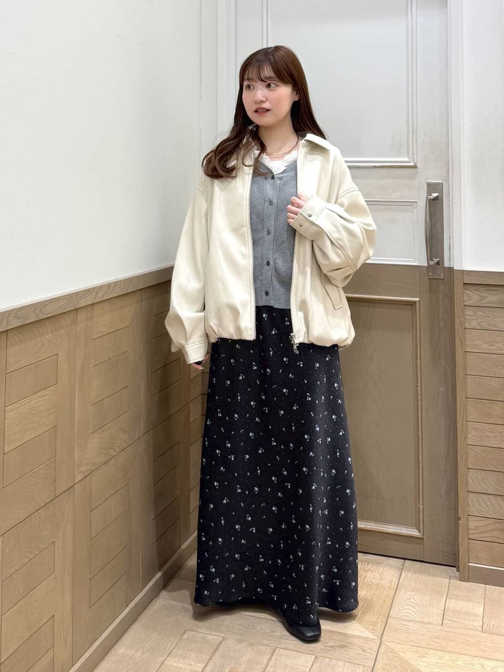 ブラック系のスカート、ブラック系のブーツ、ホワイト系のブルゾンを着用したレディースの冬コーディネートの6枚目の写真