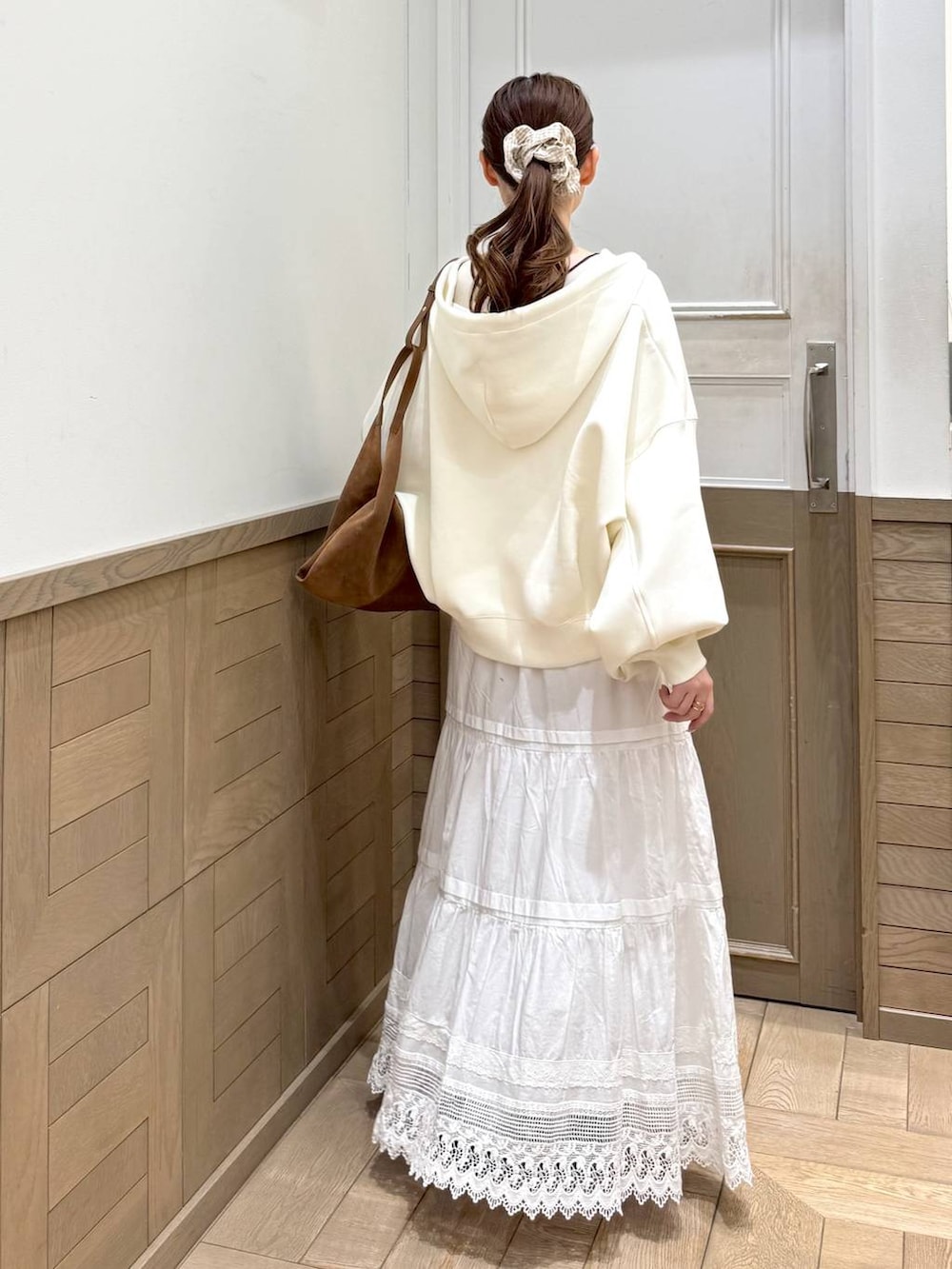 ベージュ系のパーカー、ブラウン系のショルダーバッグ、ホワイト系のスカートを着用したレディースの冬コーディネートの4枚目の写真