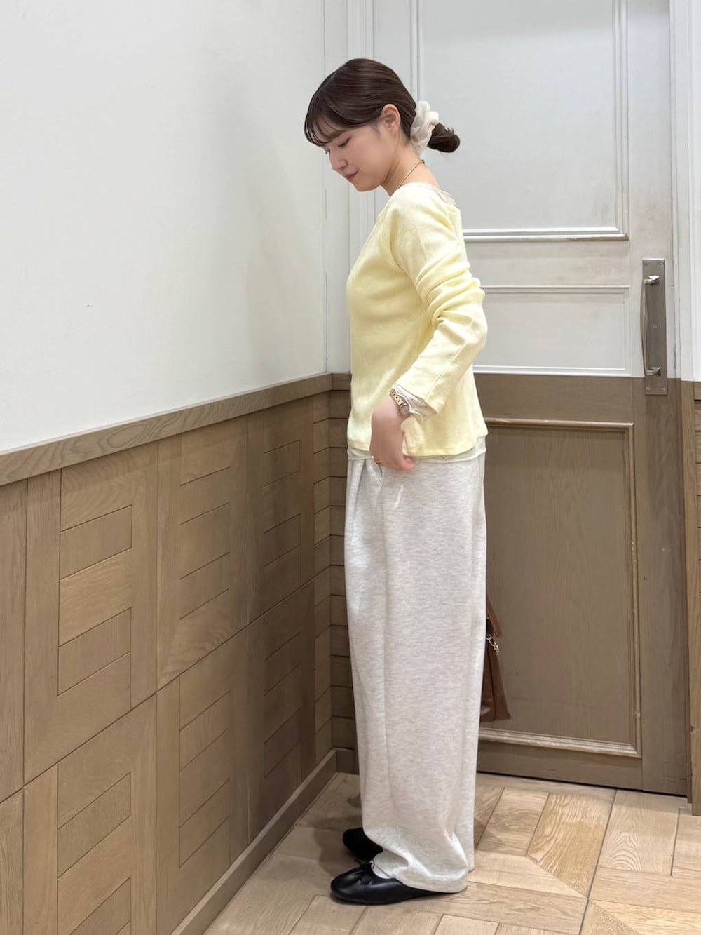 グレー系のスウェットパンツ、ブラウン系のショルダーバッグ、イエロー系のTシャツ/カットソーを着用したレディースの冬コーディネートの3枚目の写真