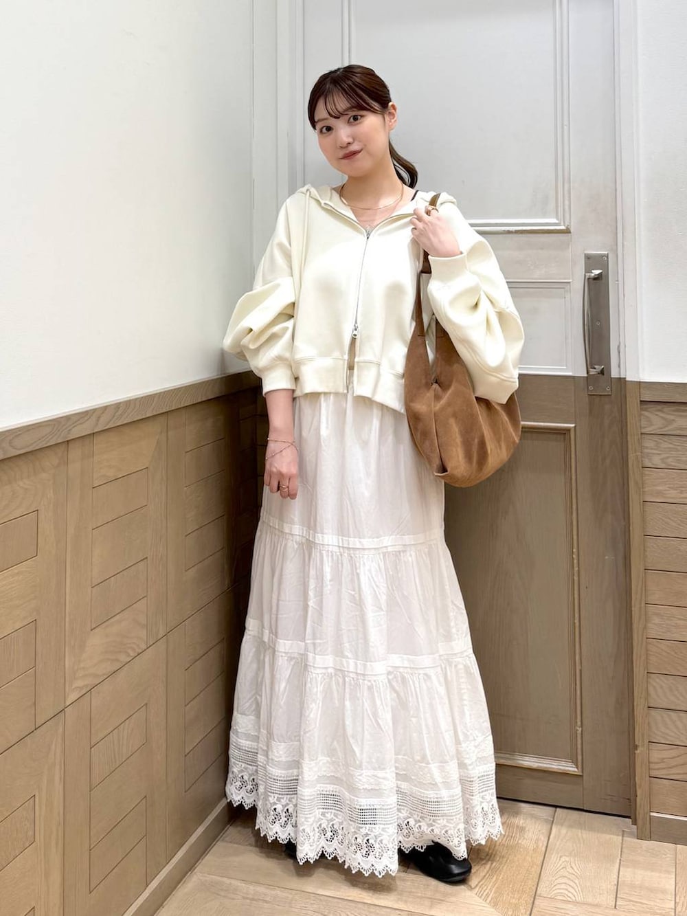 ベージュ系のパーカー、ブラウン系のショルダーバッグ、ホワイト系のスカートを着用したレディースの冬コーディネートの5枚目の写真