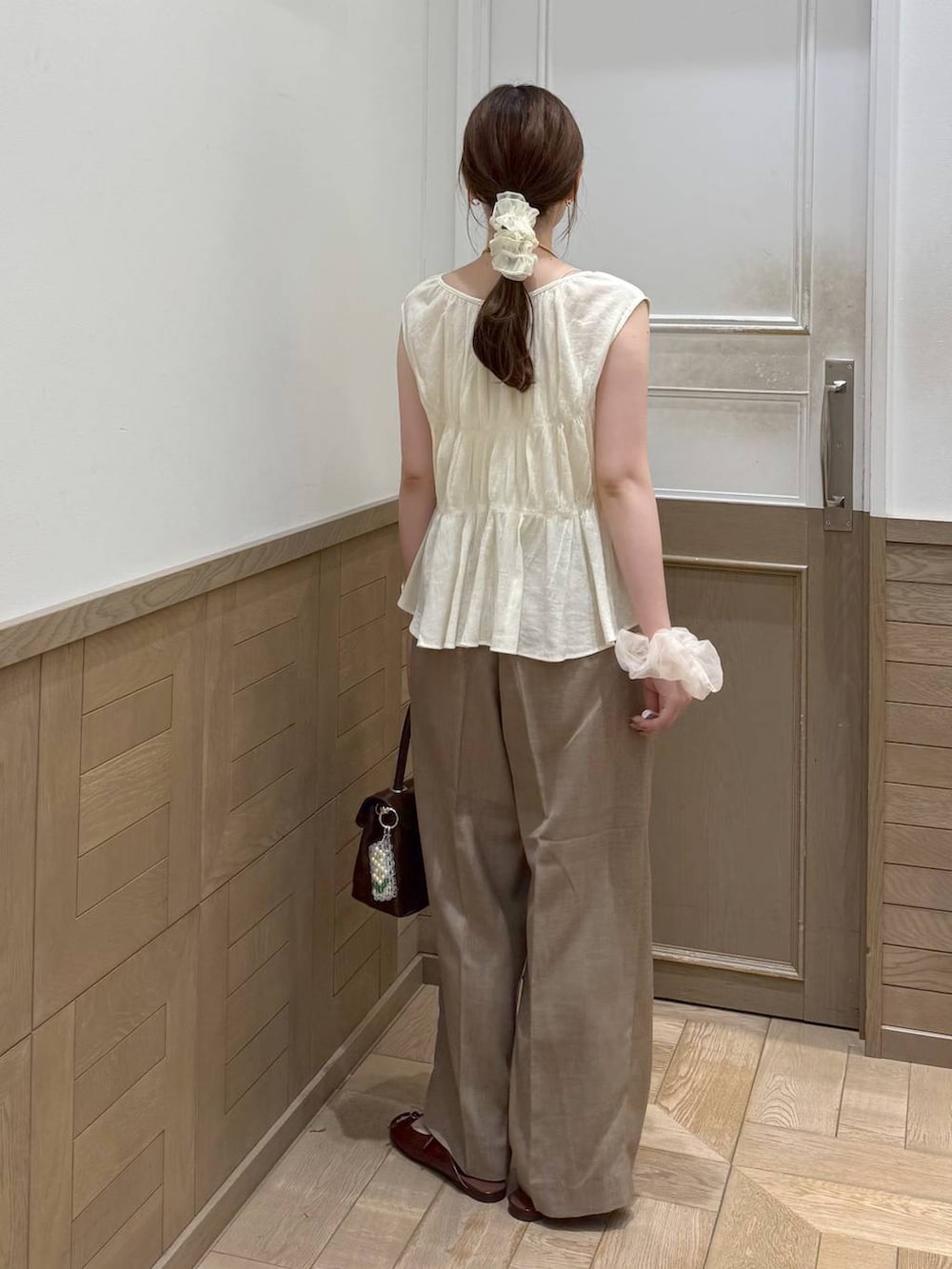 ベージュ系のスラックス、ブラウン系のサンダル、ブラウン系のボストンバッグを着用したレディースの夏コーディネートの4枚目の写真