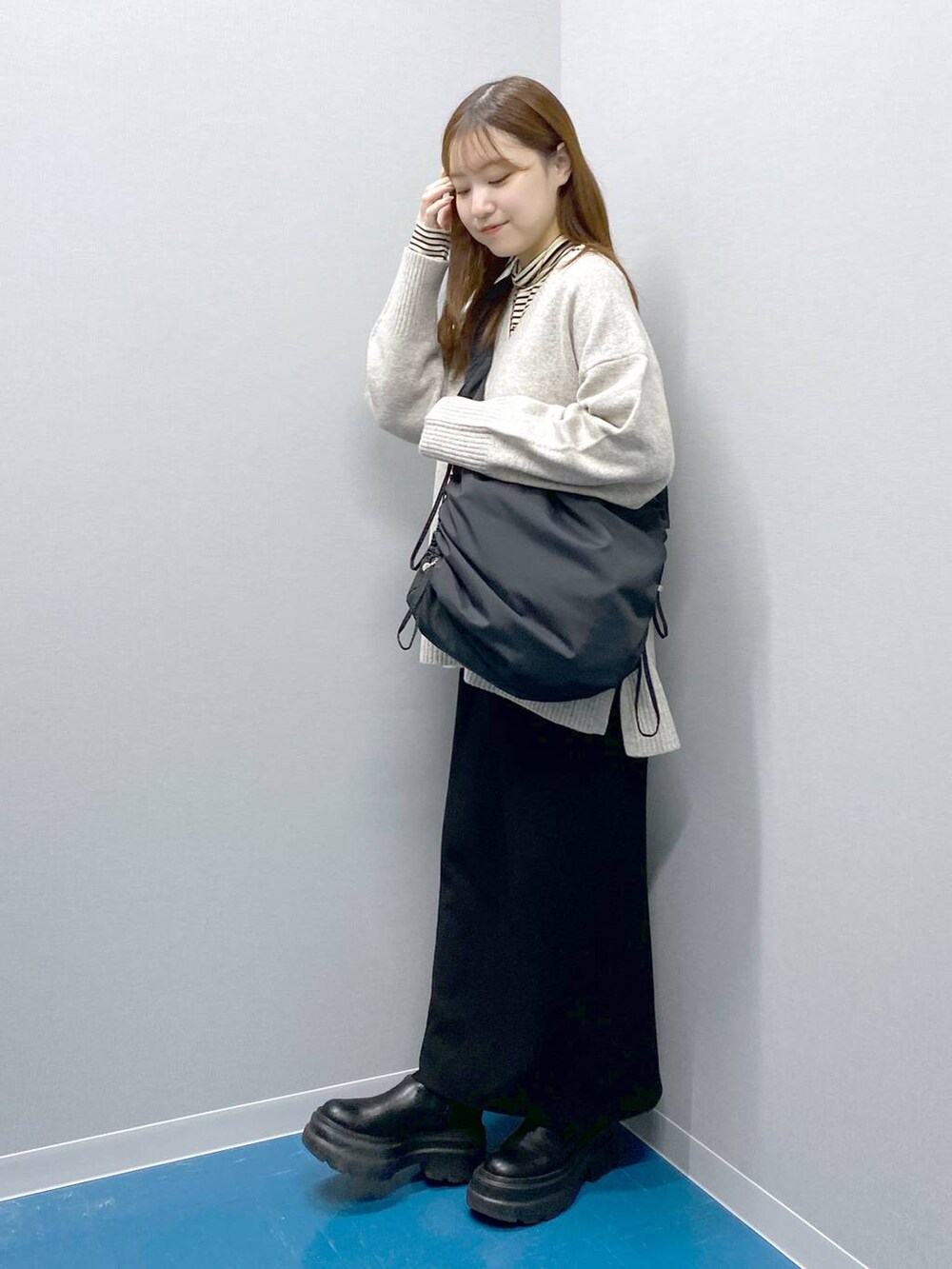 ホワイト系のTシャツ/カットソー、グレー系のニット/セーター、ブラック系のショルダーバッグを着用したレディースの冬コーディネートの6枚目の写真