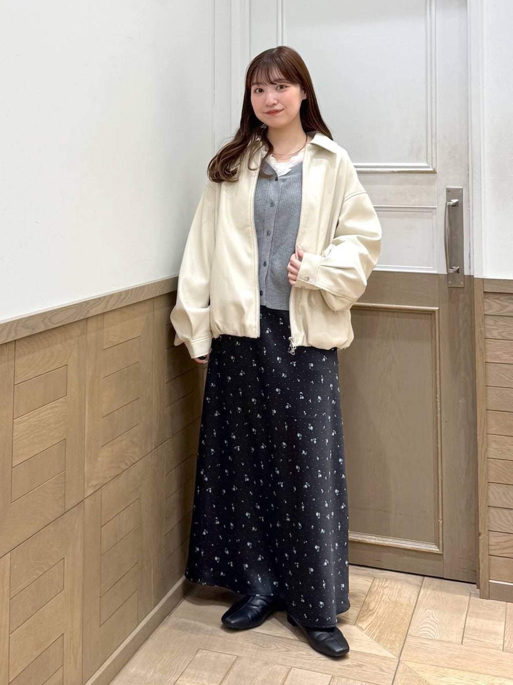 ブラック系のスカート、ブラック系のブーツ、ホワイト系のブルゾンを着用したレディースの冬コーディネートの2枚目の写真