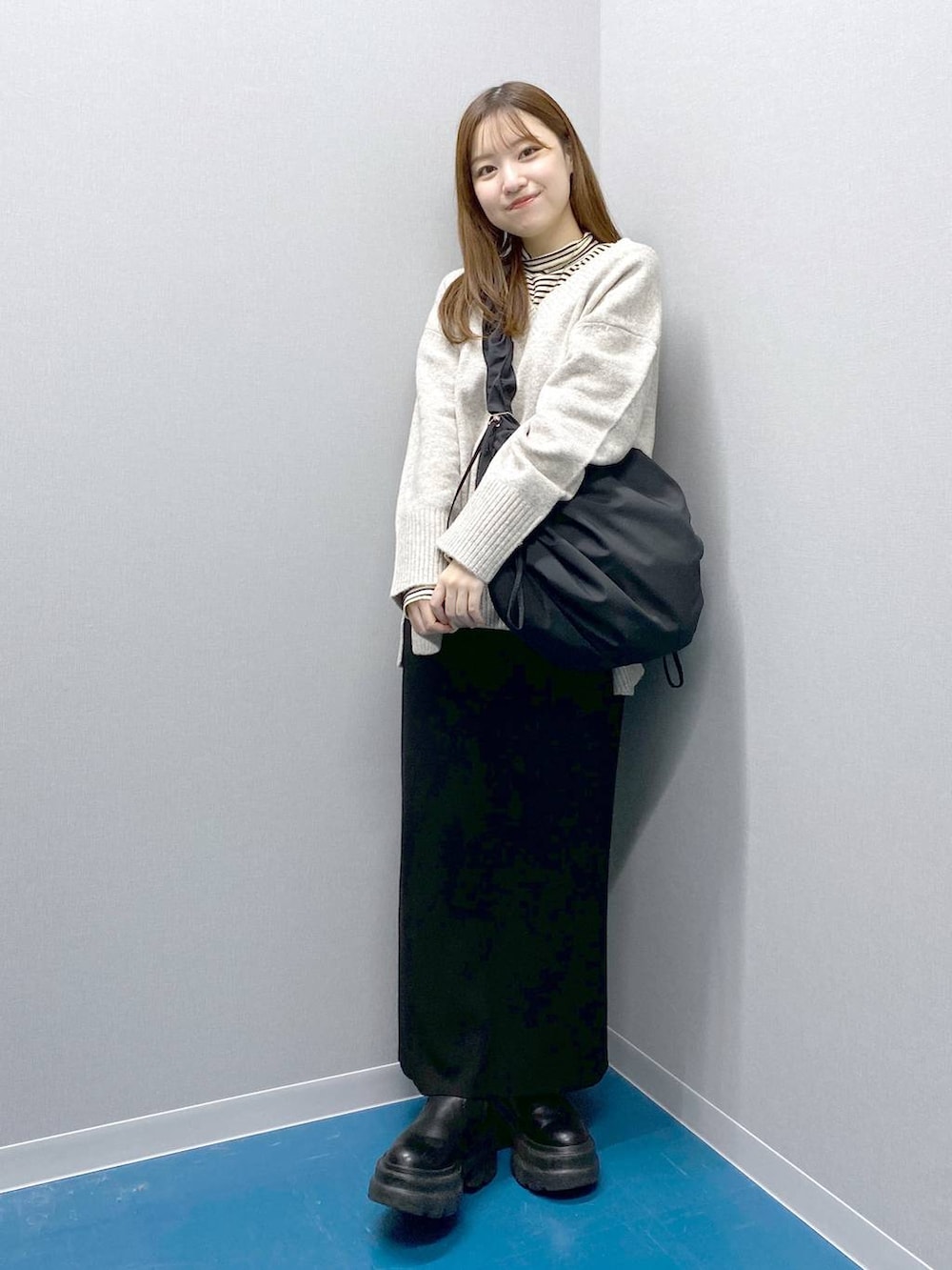 ホワイト系のTシャツ/カットソー、グレー系のニット/セーター、ブラック系のショルダーバッグを着用したレディースの冬コーディネートの2枚目の写真