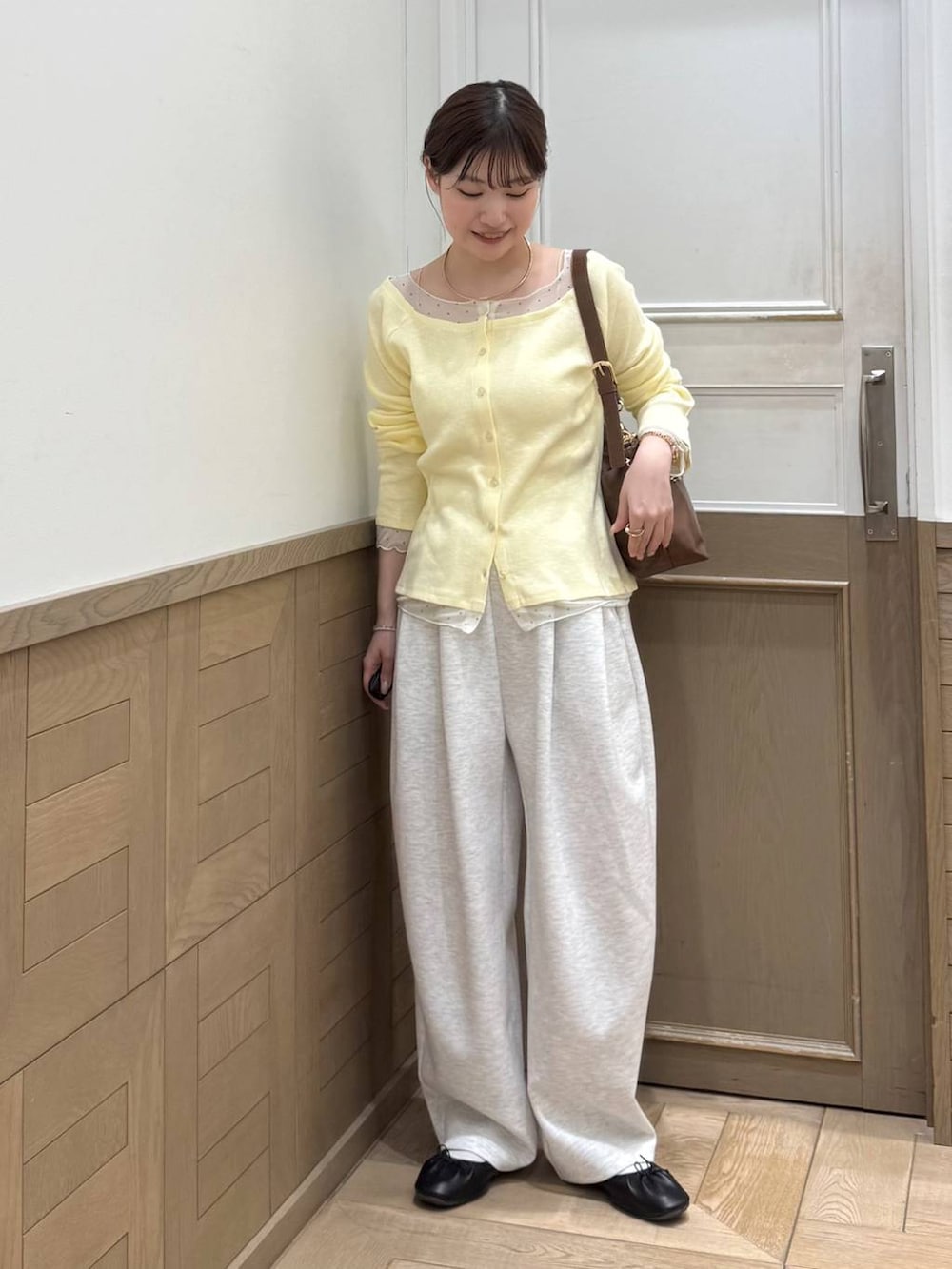 グレー系のスウェットパンツ、ブラウン系のショルダーバッグ、イエロー系のTシャツ/カットソーを着用したレディースの冬コーディネートの2枚目の写真