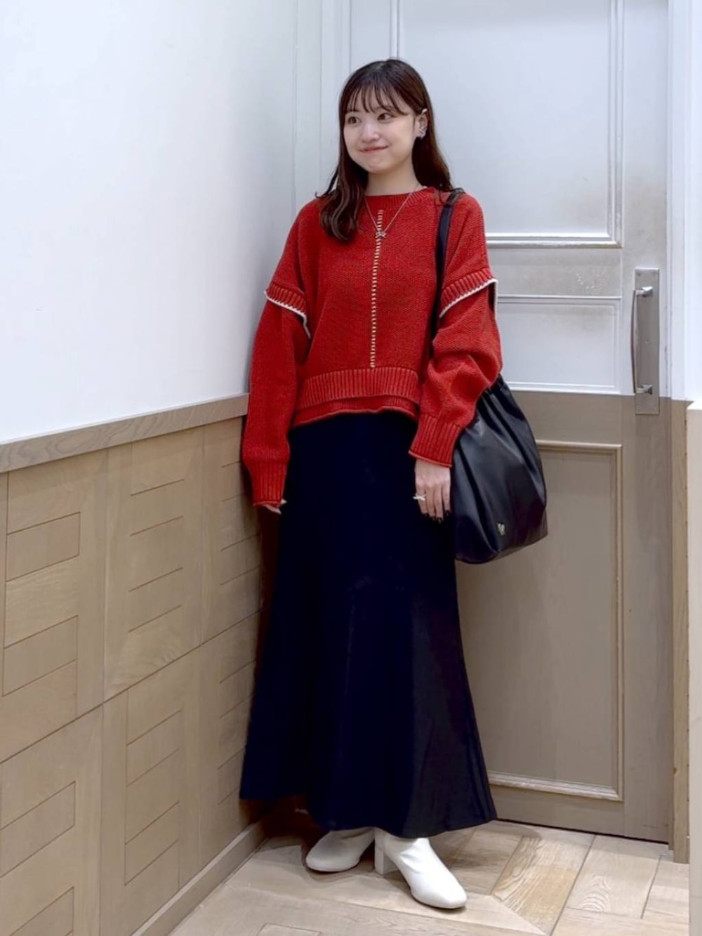 レッド系のニット/セーター、ホワイト系のブーツ、ブラック系のショルダーバッグを着用したレディースの秋コーディネートの6枚目の写真