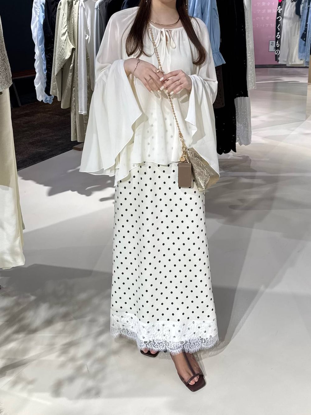 ゴールド系のショルダーバッグ、ブラウン系のサンダル、ホワイト系のスカートを着用したレディースの春コーディネートの4枚目の写真