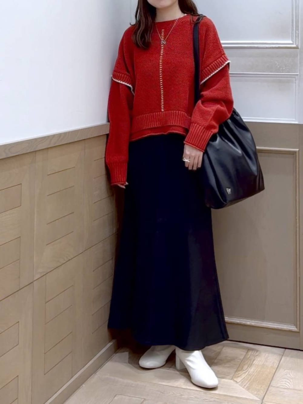 レッド系のニット/セーター、ホワイト系のブーツ、ブラック系のショルダーバッグを着用したレディースの秋コーディネートの5枚目の写真