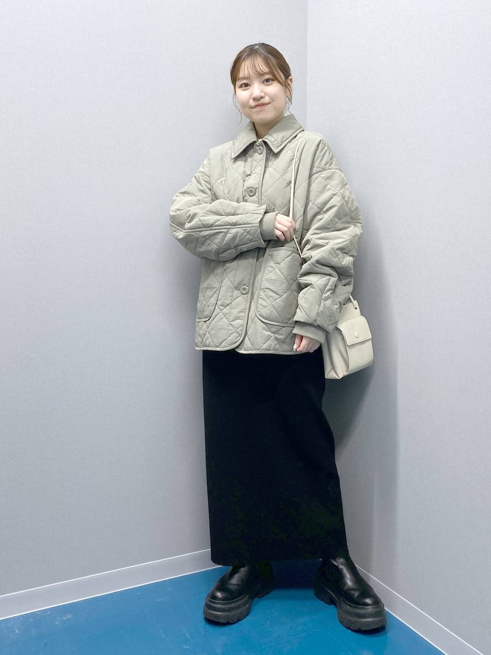 ホワイト系のショルダーバッグ、ブラック系のブーツ、ブラック系のスカートを着用したレディースの冬コーディネートの6枚目の写真