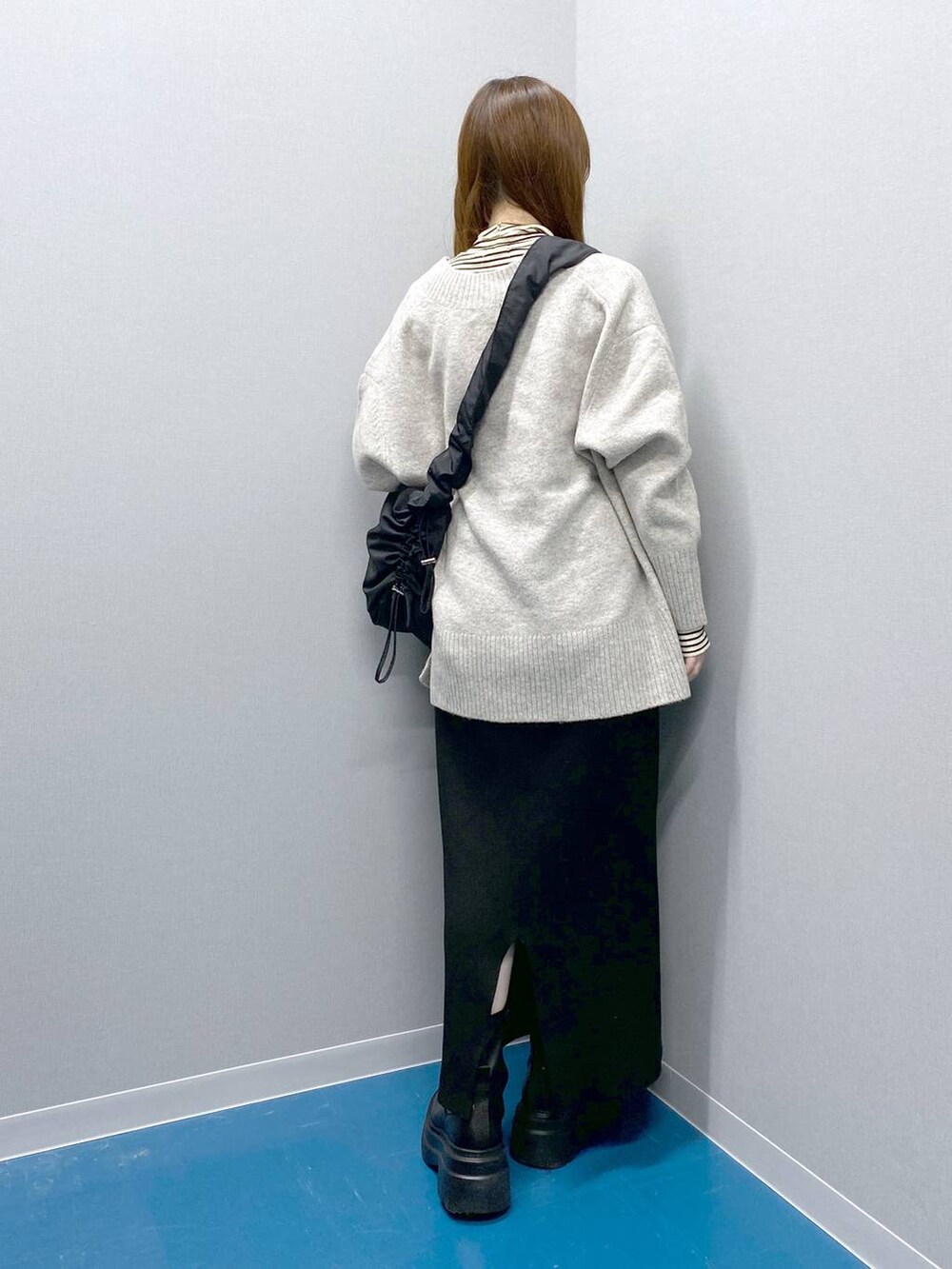 ホワイト系のTシャツ/カットソー、グレー系のニット/セーター、ブラック系のショルダーバッグを着用したレディースの冬コーディネートの4枚目の写真