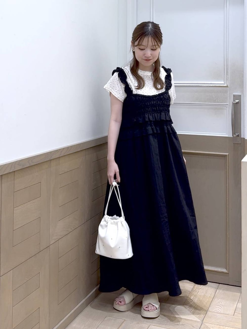 ホワイト系のショルダーバッグ、ホワイト系のサンダル、ブラック系のワンピースを着用したレディースの夏コーディネートの6枚目の写真