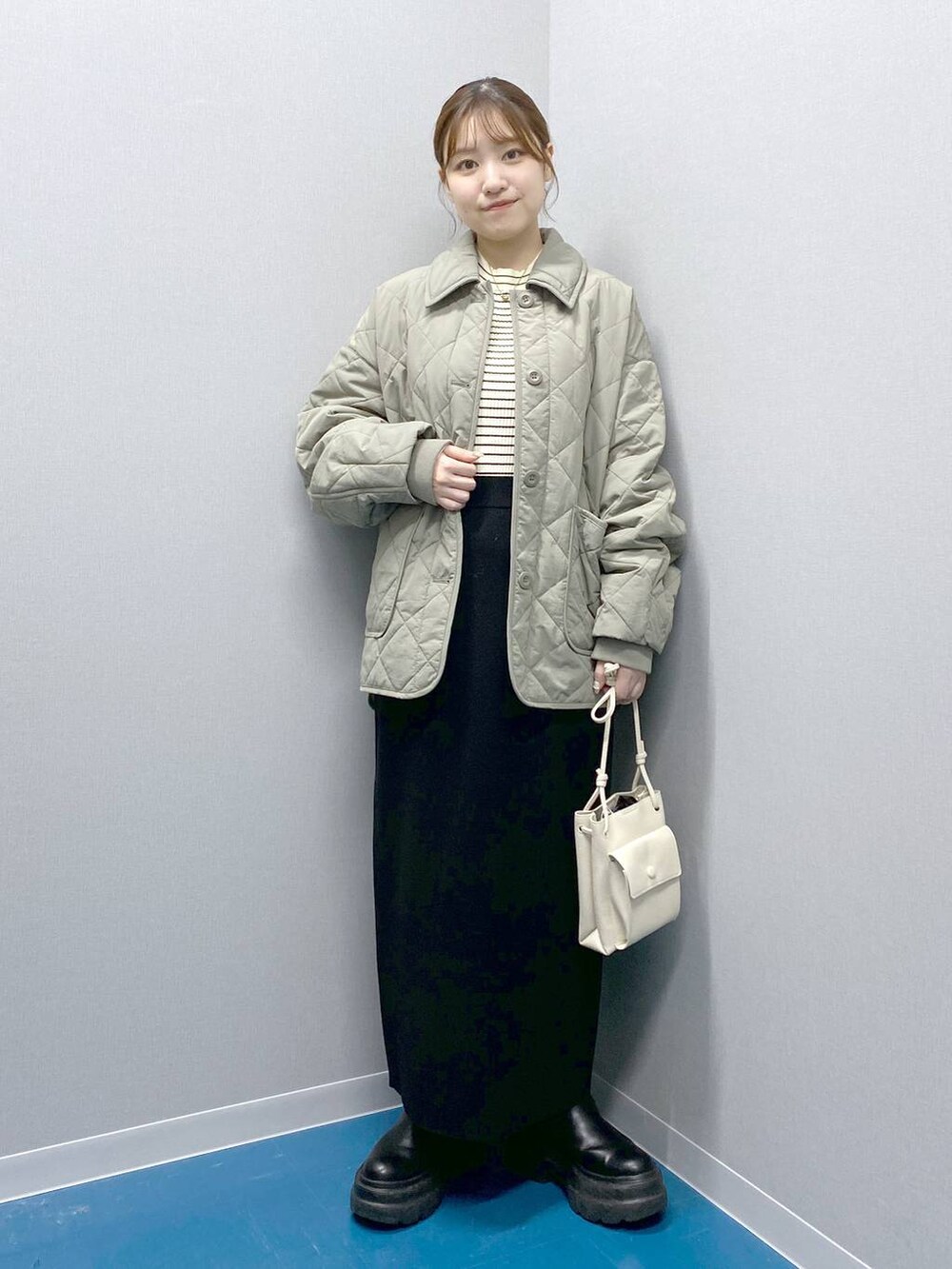 ホワイト系のショルダーバッグ、ブラック系のブーツ、ブラック系のスカートを着用したレディースの冬コーディネートの2枚目の写真