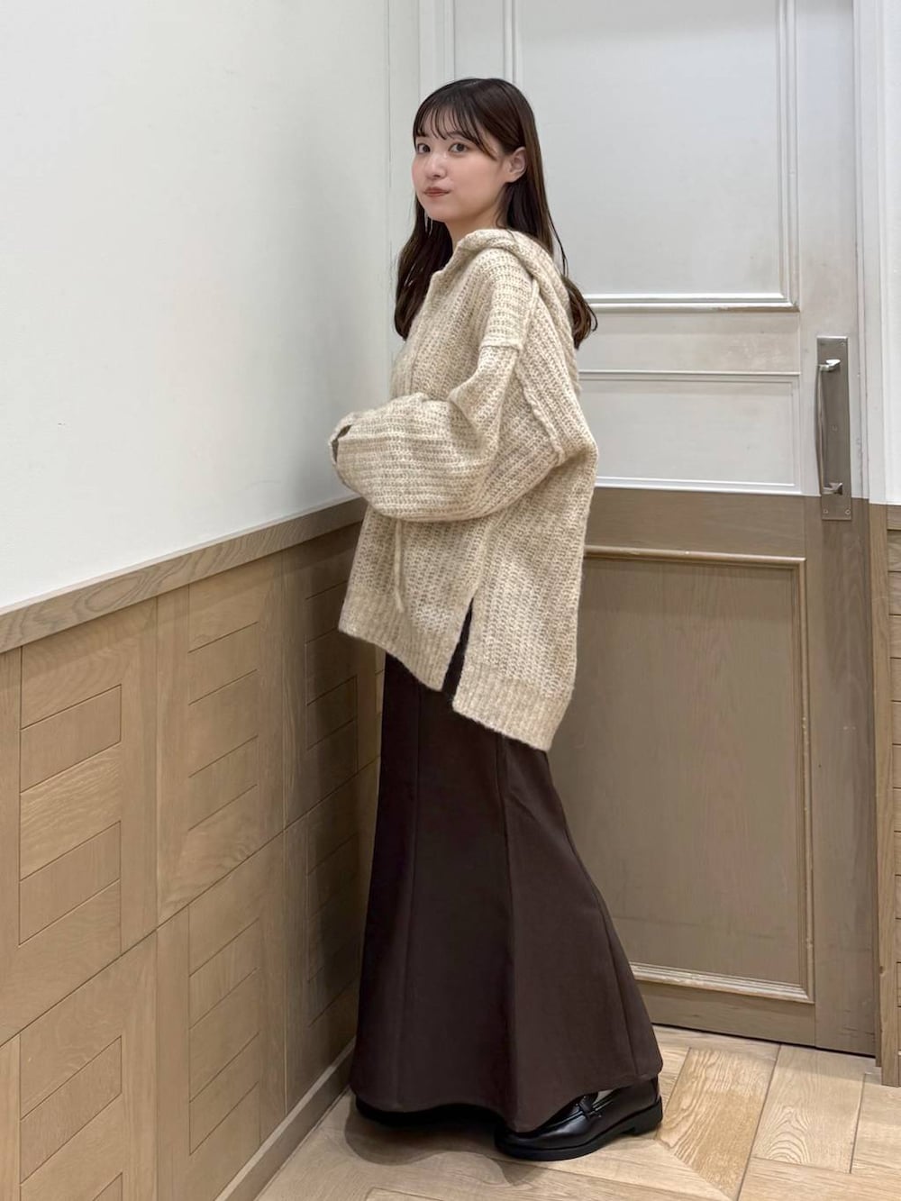 ホワイト系のニット/セーター、ブラック系のローファー、ブラウン系のスカートを着用したレディースの秋コーディネートの6枚目の写真