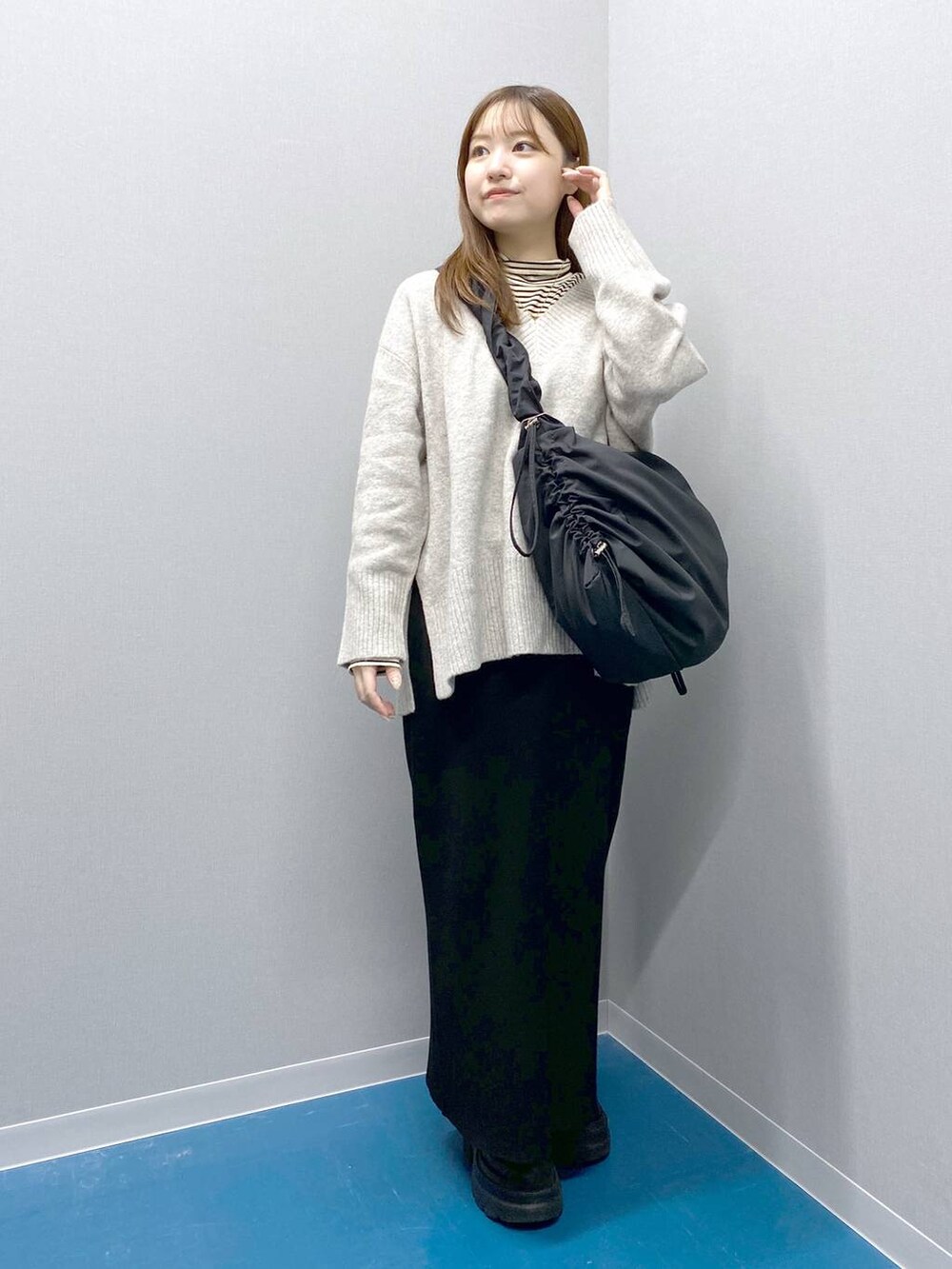 ホワイト系のTシャツ/カットソー、グレー系のニット/セーター、ブラック系のショルダーバッグを着用したレディースの冬コーディネートの5枚目の写真