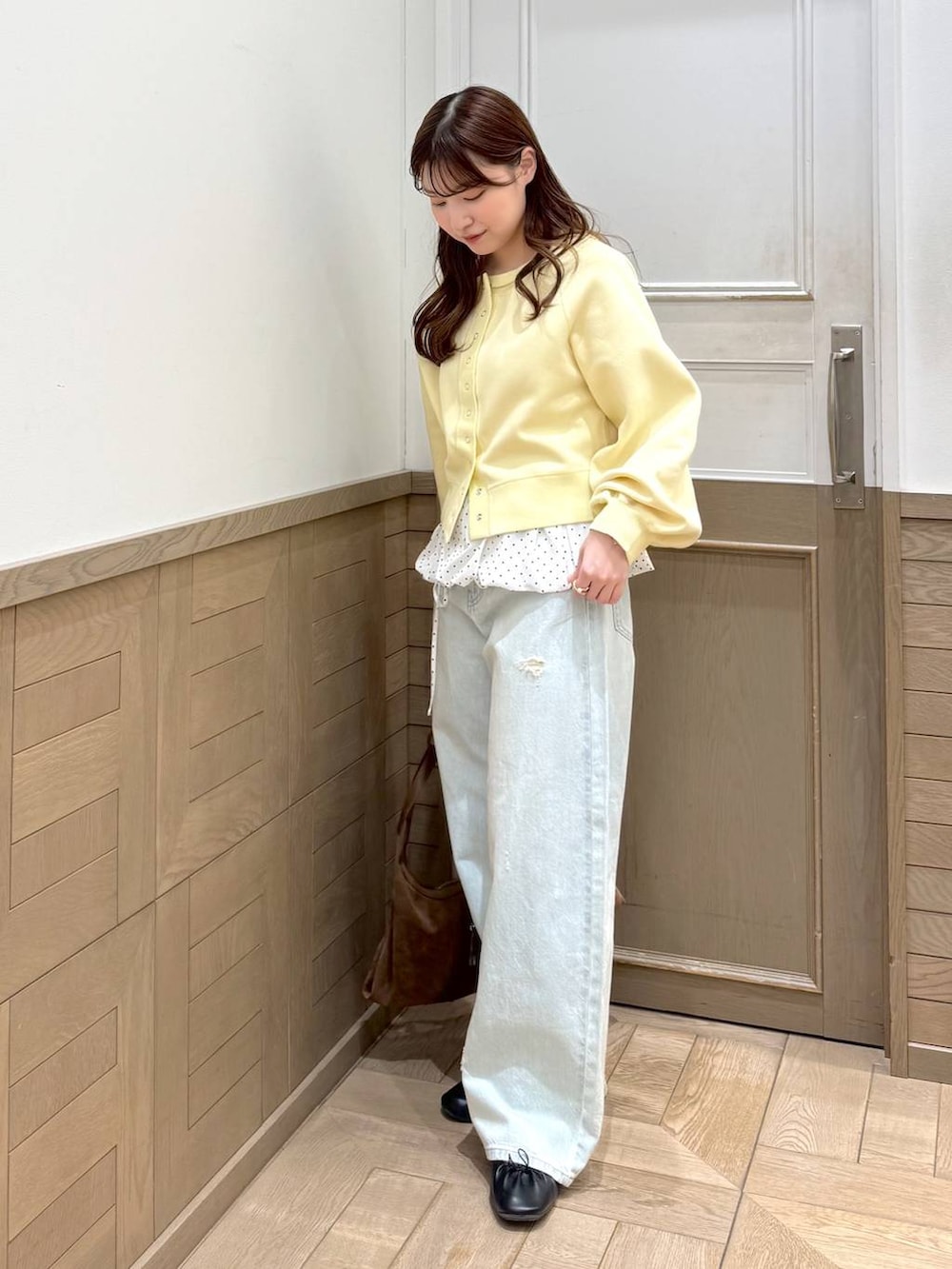 ブルー系のデニムパンツ、ブラウン系のショルダーバッグ、イエロー系のスウェットを着用したレディースの冬コーディネートの4枚目の写真