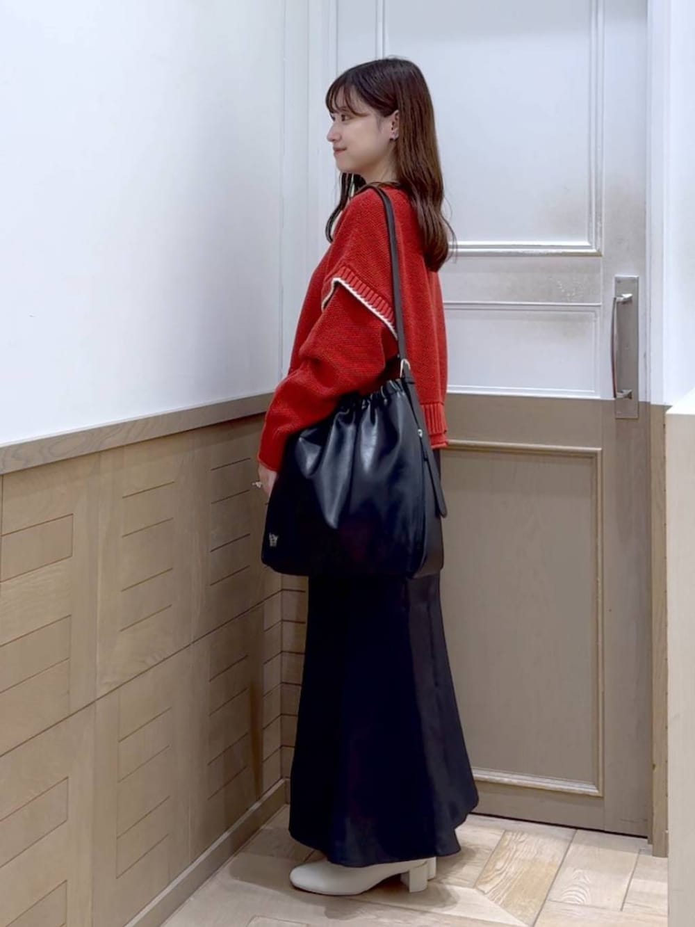 レッド系のニット/セーター、ホワイト系のブーツ、ブラック系のショルダーバッグを着用したレディースの秋コーディネートの3枚目の写真