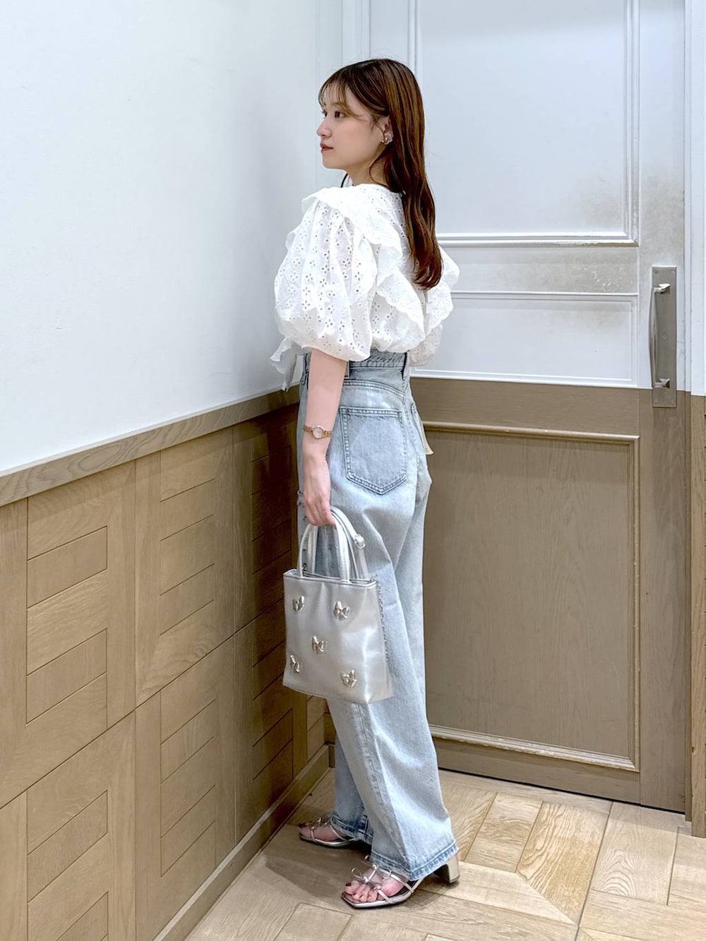 シルバー系のサンダル、ブルー系のデニムパンツ、シルバー系のショルダーバッグを着用したレディースの夏コーディネートの3枚目の写真