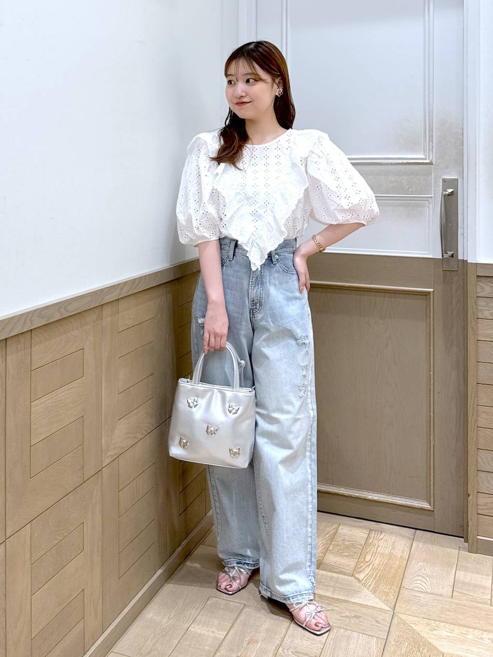 シルバー系のサンダル、ブルー系のデニムパンツ、シルバー系のショルダーバッグを着用したレディースの夏コーディネートの2枚目の写真