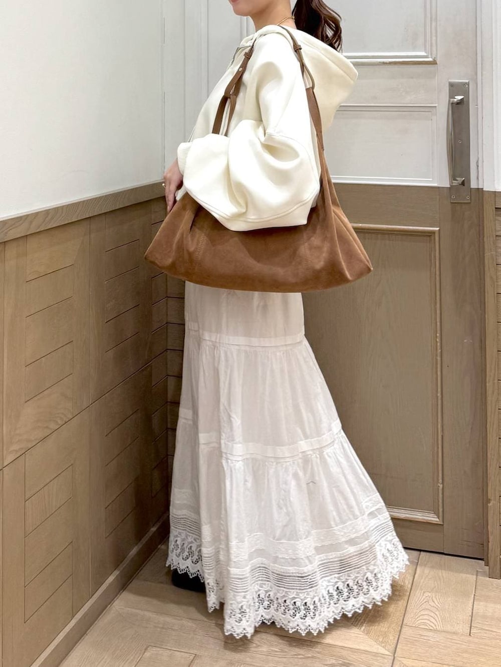 ベージュ系のパーカー、ブラウン系のショルダーバッグ、ホワイト系のスカートを着用したレディースの冬コーディネートの7枚目の写真