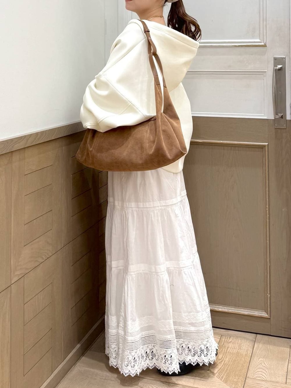 ベージュ系のパーカー、ブラウン系のショルダーバッグ、ホワイト系のスカートを着用したレディースの冬コーディネートの3枚目の写真