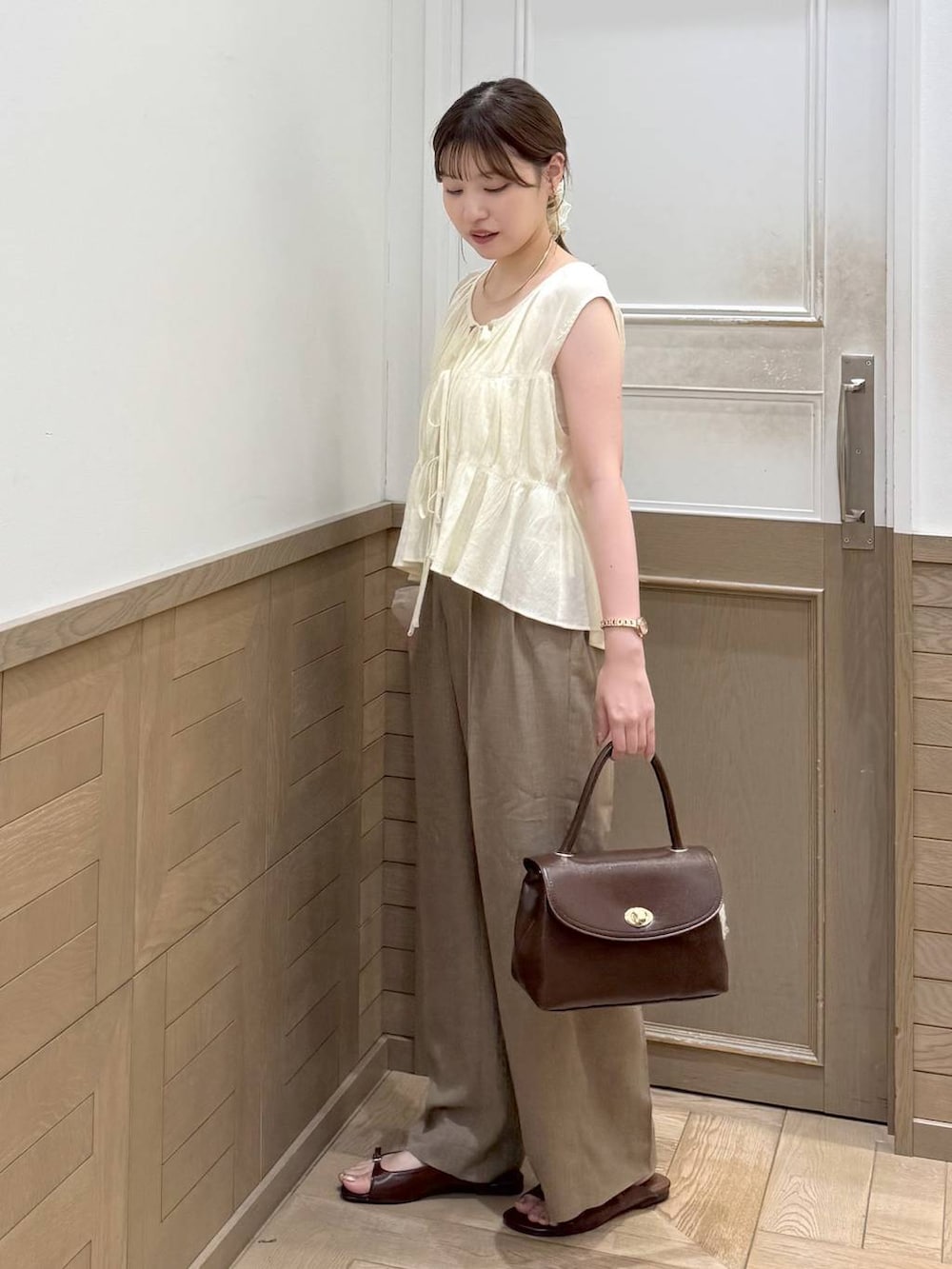 ベージュ系のスラックス、ブラウン系のサンダル、ブラウン系のボストンバッグを着用したレディースの夏コーディネートの3枚目の写真