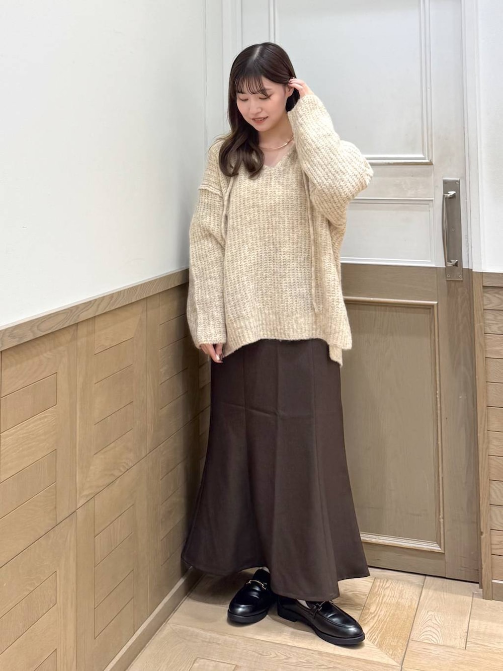 ホワイト系のニット/セーター、ブラック系のローファー、ブラウン系のスカートを着用したレディースの秋コーディネートの2枚目の写真