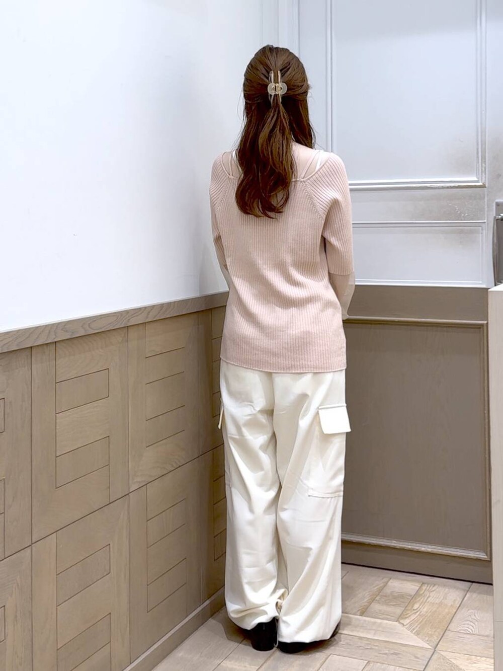 ブラック系のパンプス、ブラック系のショルダーバッグ、ホワイト系のスラックスを着用したレディースの秋コーディネートの2枚目の写真