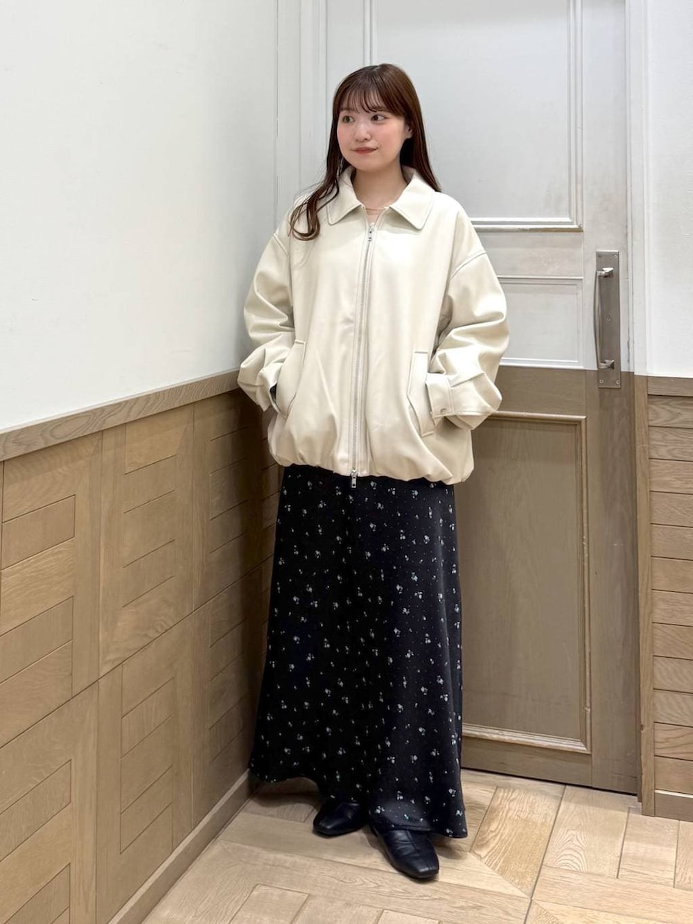 ブラック系のスカート、ブラック系のブーツ、ホワイト系のブルゾンを着用したレディースの冬コーディネートの4枚目の写真