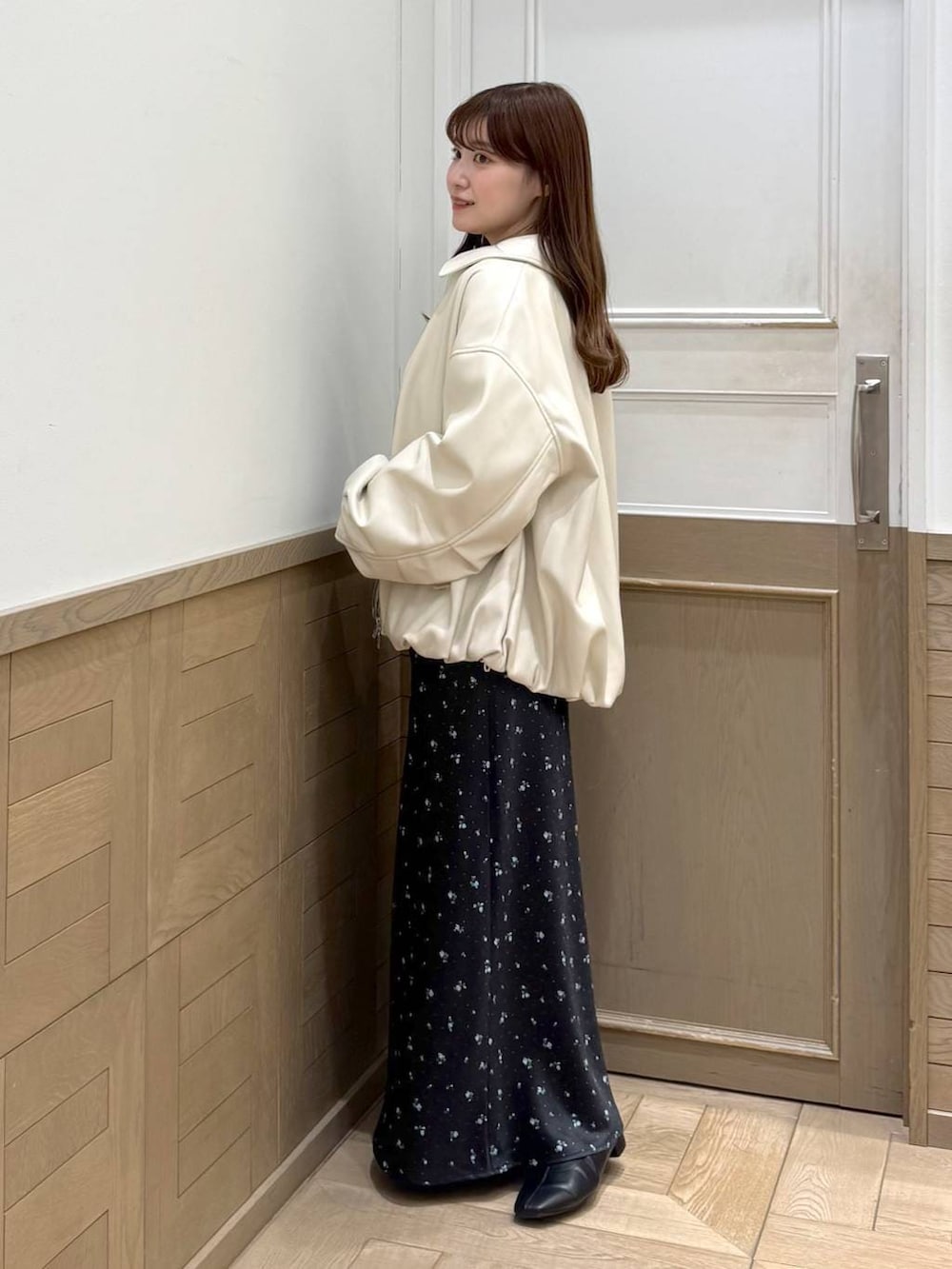 ブラック系のスカート、ブラック系のブーツ、ホワイト系のブルゾンを着用したレディースの冬コーディネートの3枚目の写真