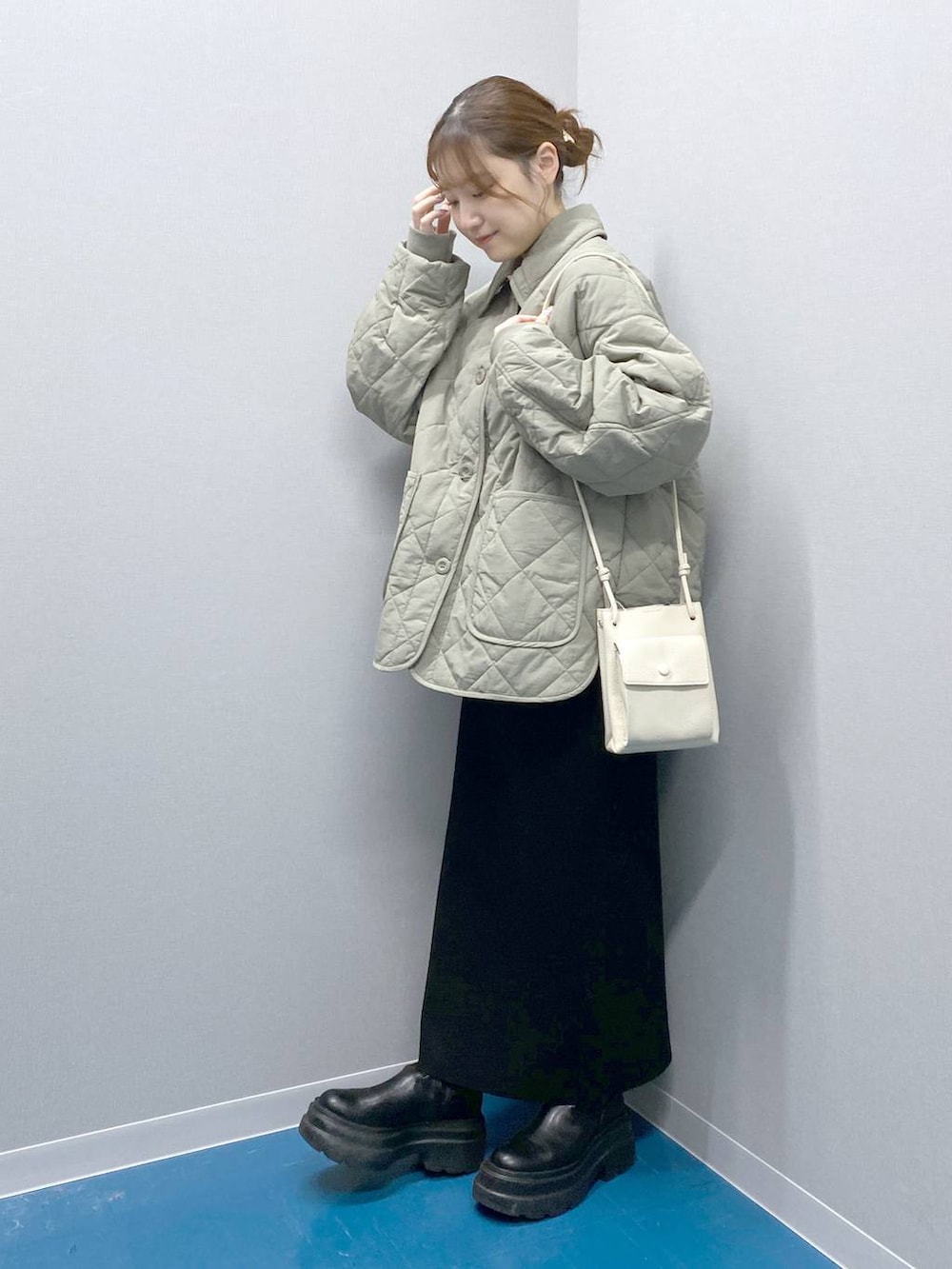 ホワイト系のショルダーバッグ、ブラック系のブーツ、ブラック系のスカートを着用したレディースの冬コーディネートの4枚目の写真