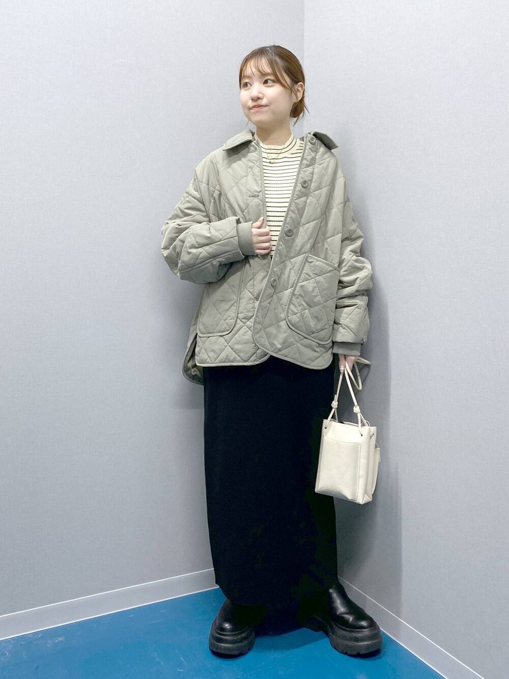 ホワイト系のショルダーバッグ、ブラック系のブーツ、ブラック系のスカートを着用したレディースの冬コーディネートの3枚目の写真