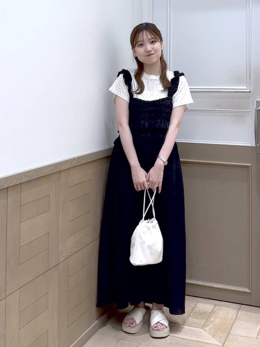 ホワイト系のショルダーバッグ、ホワイト系のサンダル、ブラック系のワンピースを着用したレディースの夏コーディネートの2枚目の写真