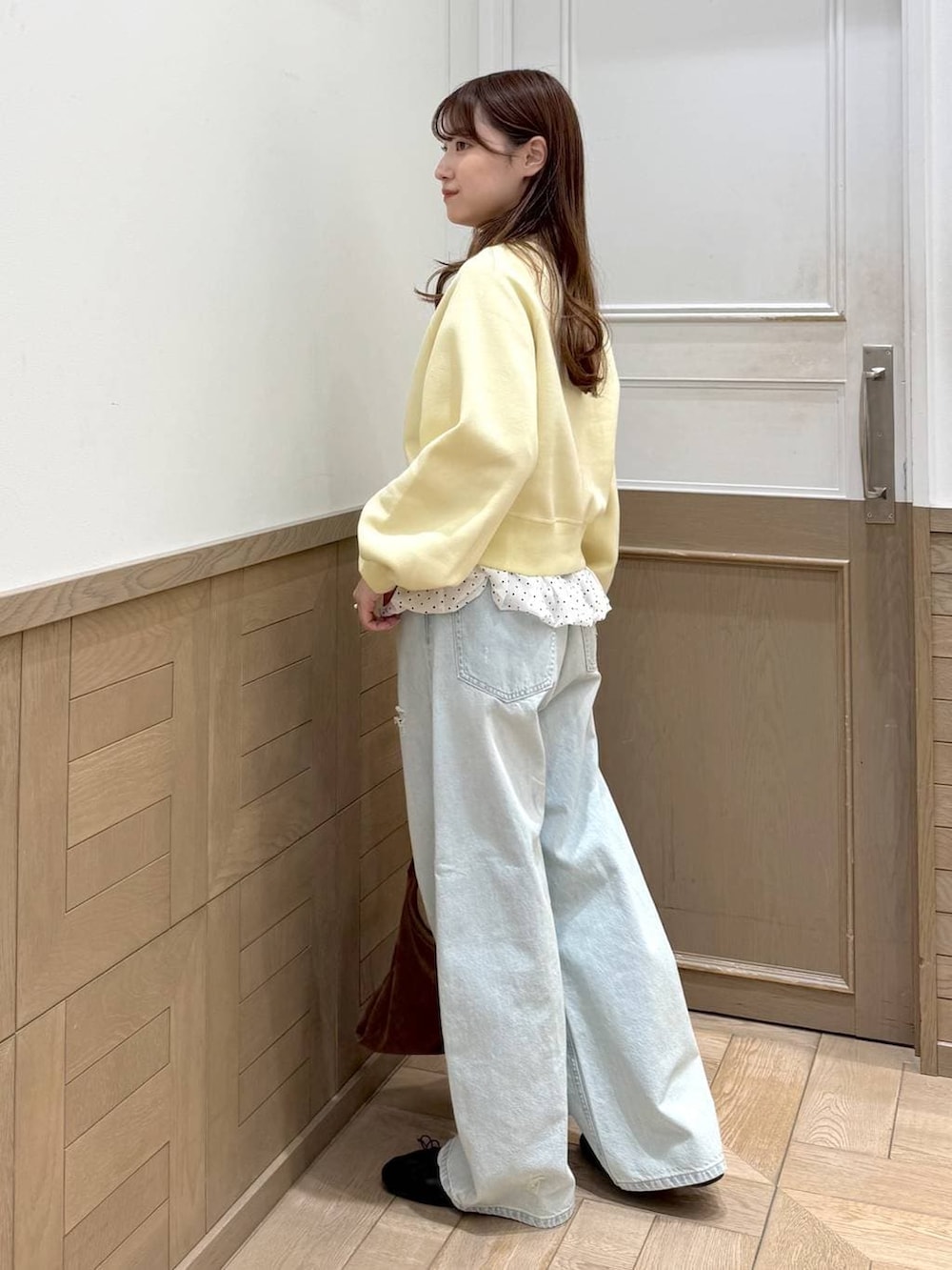 ブルー系のデニムパンツ、ブラウン系のショルダーバッグ、イエロー系のスウェットを着用したレディースの冬コーディネートの2枚目の写真