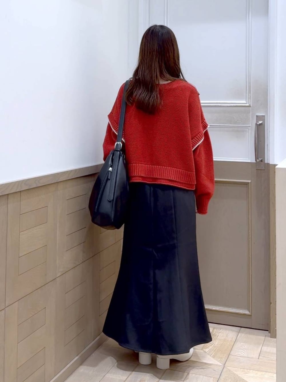 レッド系のニット/セーター、ホワイト系のブーツ、ブラック系のショルダーバッグを着用したレディースの秋コーディネートの4枚目の写真
