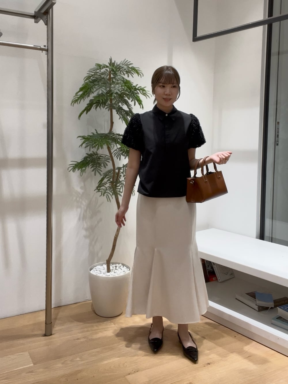ブラック系のシャツ/ブラウス、ホワイト系のスカート、ブラック系のローファーを着用したレディースの夏コーディネートの5枚目の写真