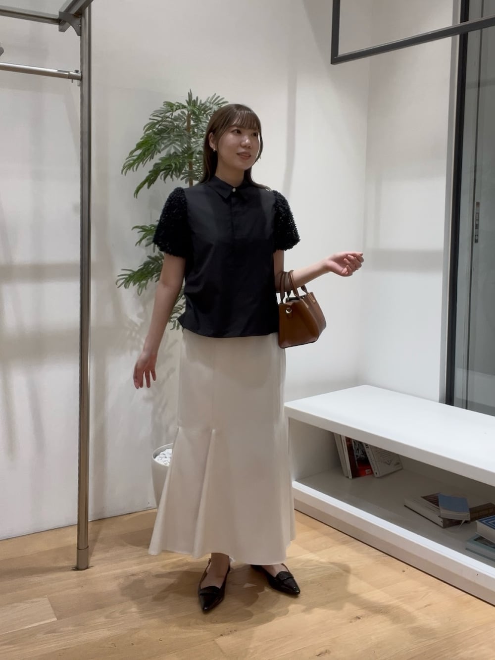 ブラック系のシャツ/ブラウス、ホワイト系のスカート、ブラック系のローファーを着用したレディースの夏コーディネートの3枚目の写真