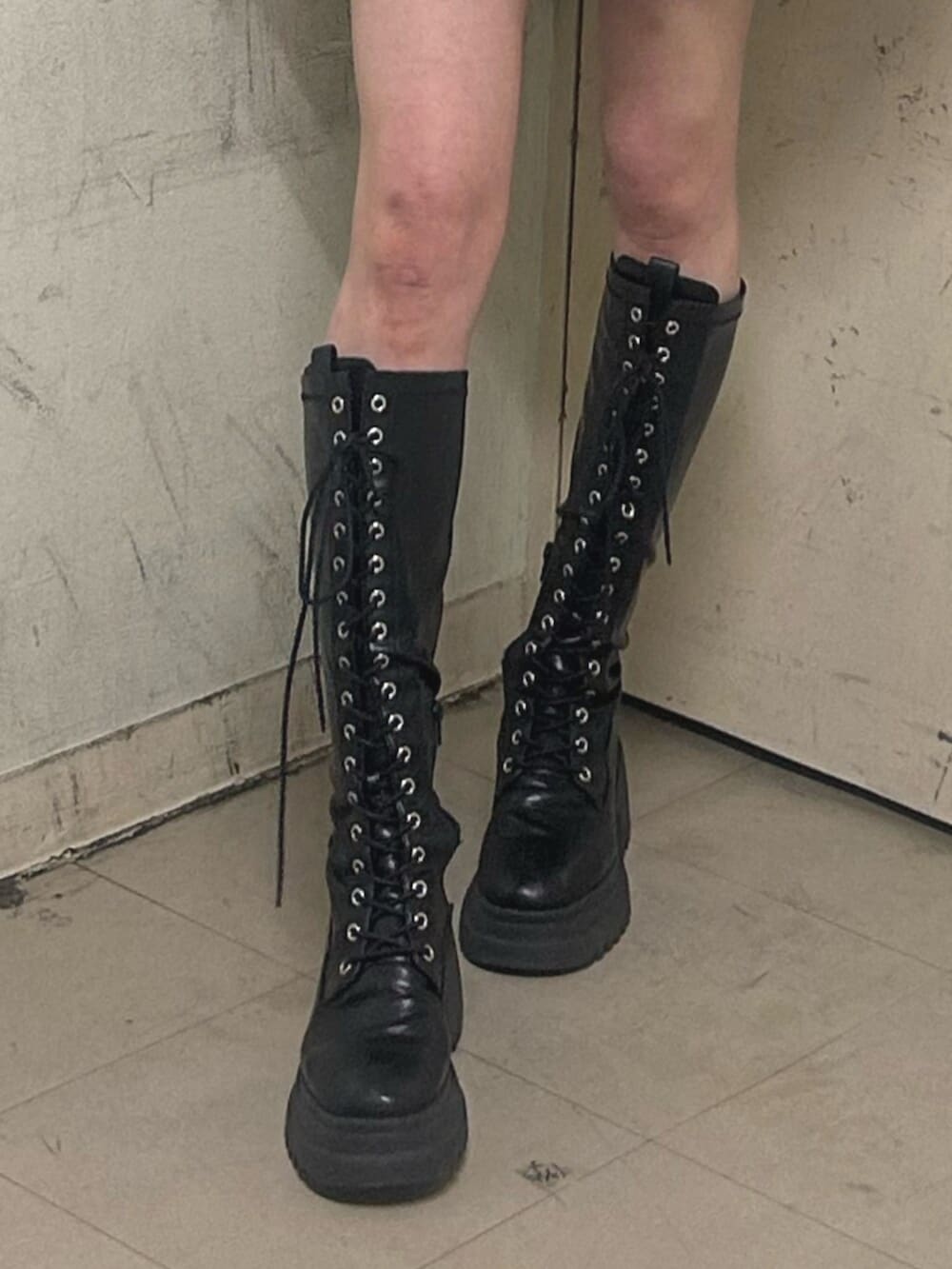 ブラック系のブーツ、ブラック系のスカート、ブラック系のパーカーを着用したレディースの春コーディネートの6枚目の写真