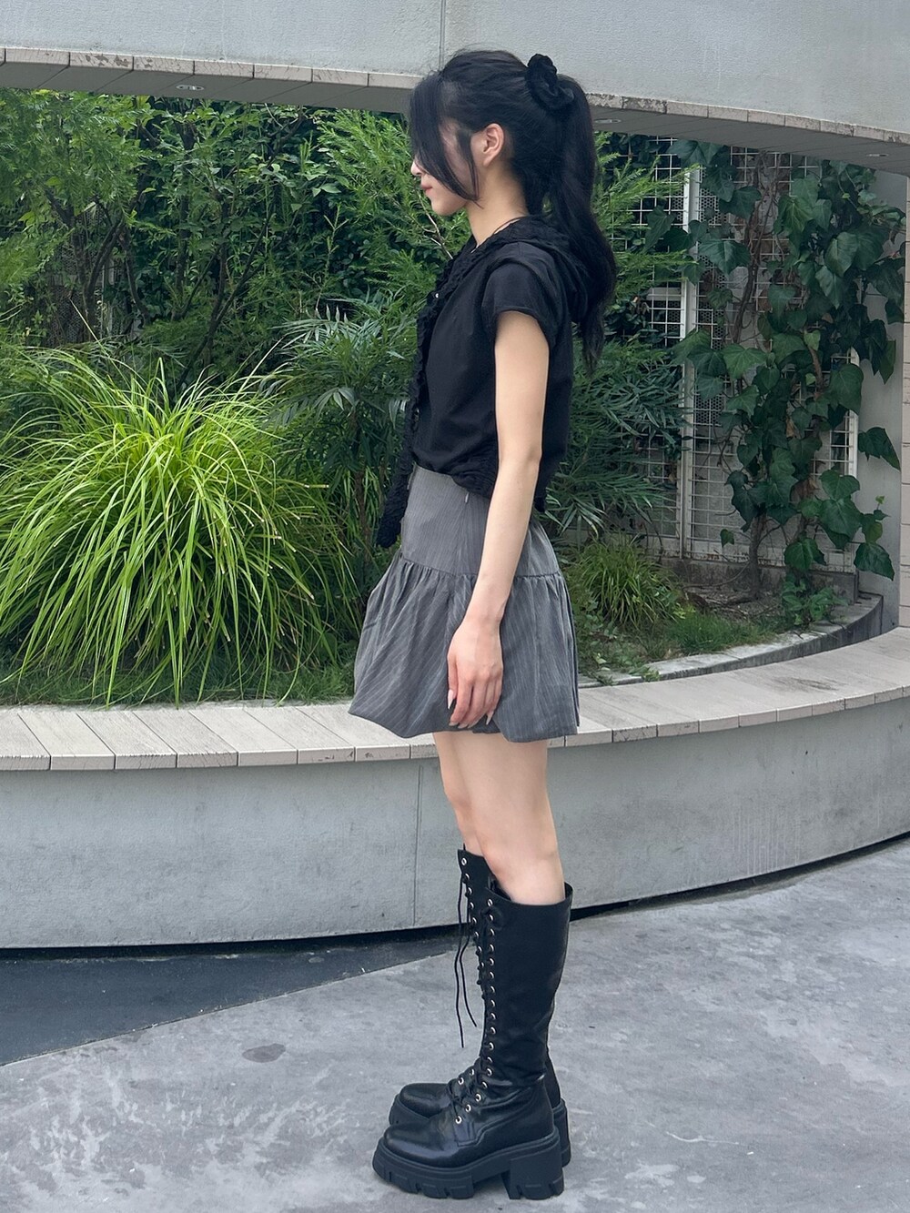 グレー系のスカート、ブラック系のTシャツ/カットソー、ブラック系のブーツを着用したレディースの夏コーディネートの2枚目の写真