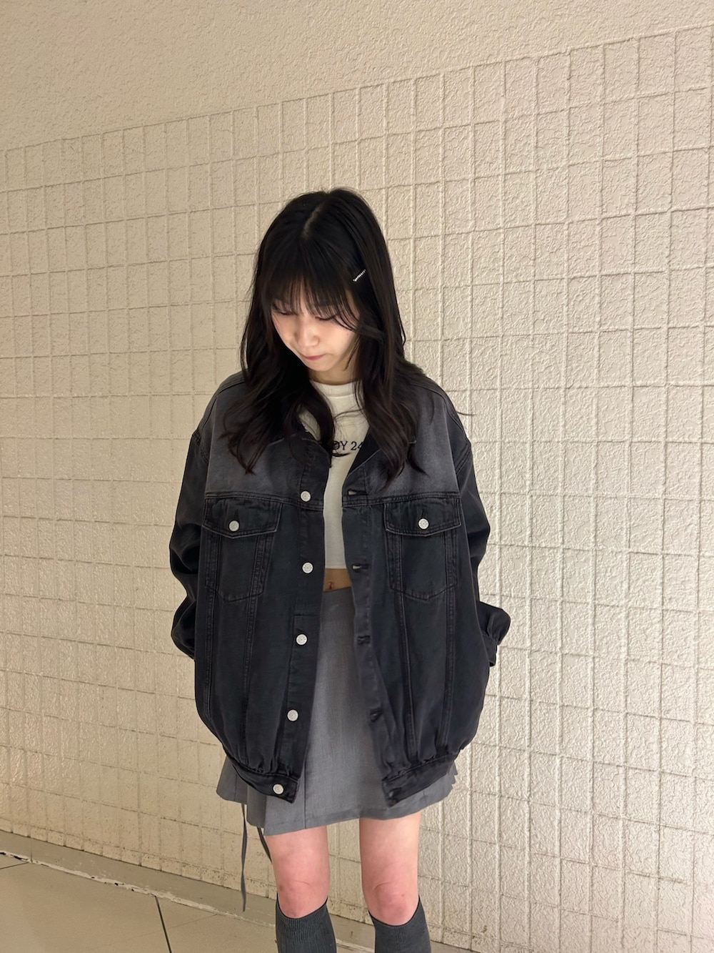 ブラック系のデニムジャケット、ホワイト系のTシャツ/カットソー、グレー系のスカートを着用したレディースの春コーディネートの3枚目の写真