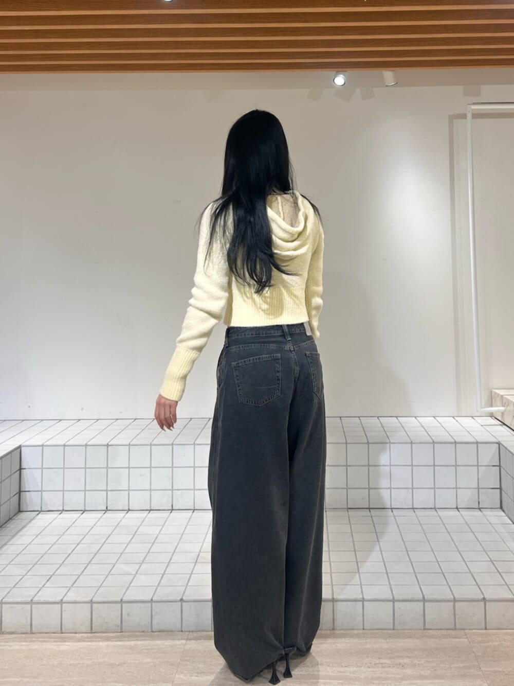 ブラック系のパンプス、ブルー系のデニムパンツ、イエロー系のパーカーを着用したレディースの冬コーディネートの3枚目の写真